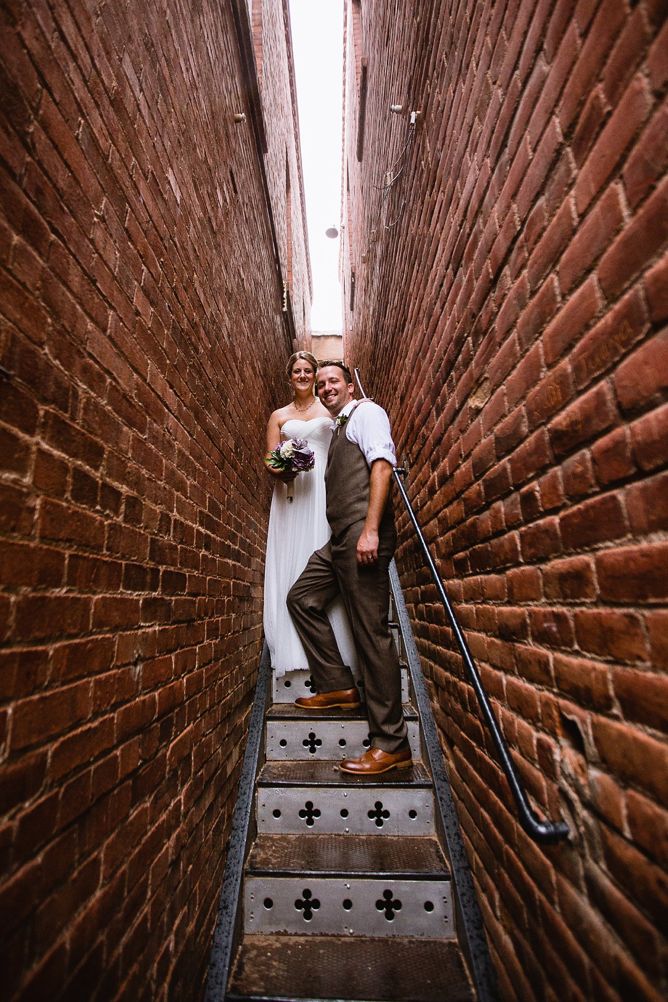 Bride and Groom taking shelter from rain in small stairwell in Bisbee Arizona by PMA Photography