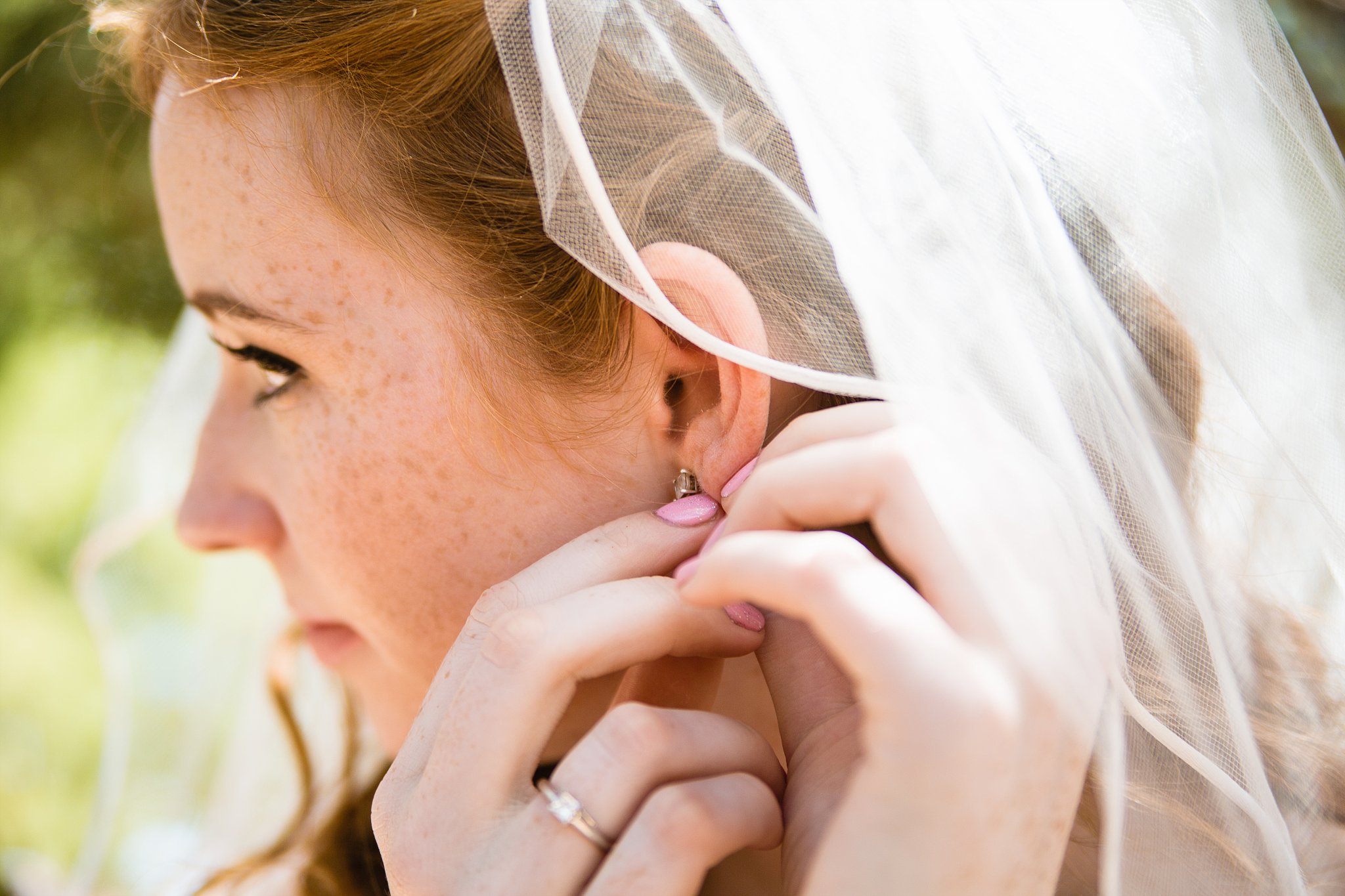 Bride putting in her earring while getting ready on her wedding day by Arizona wedding photographer PMA Photography.