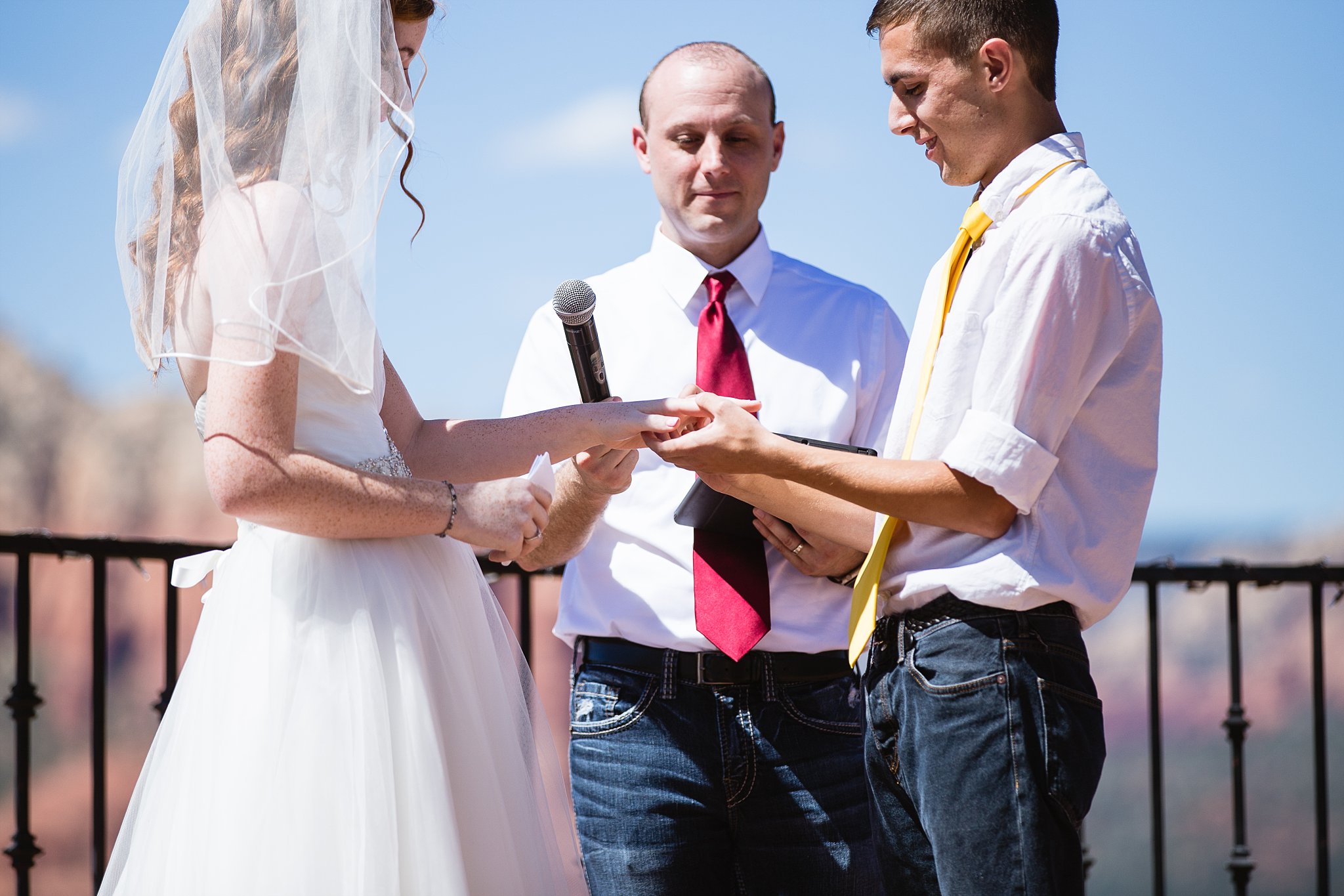 Bride and groom exchange rings during their wedding ceremony at Sky Ranch Lodge by Arizona wedding photographer PMA Photography.