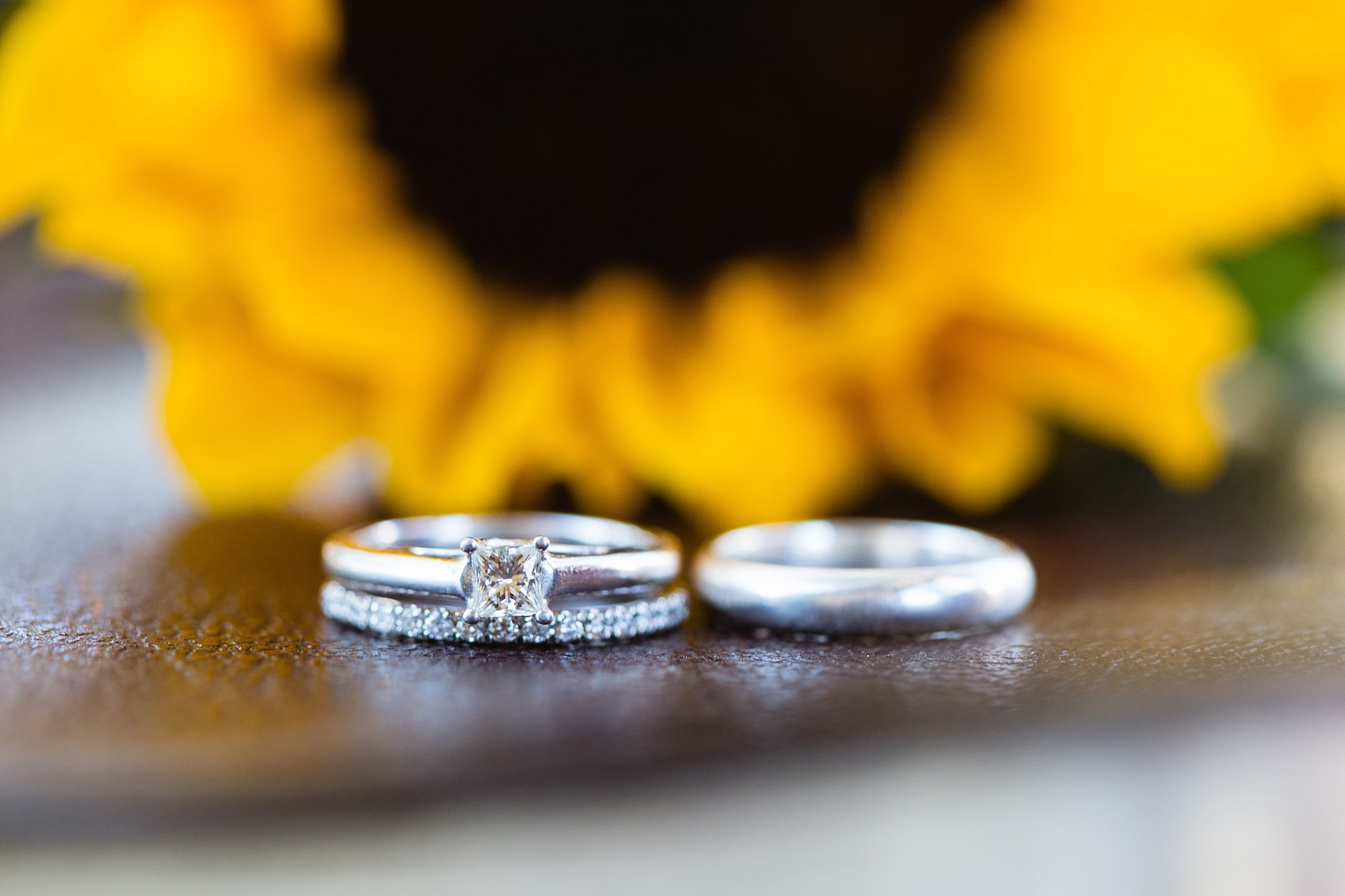 Simple wedding rings on the family bible in front of a sunflower by PMA Photography.