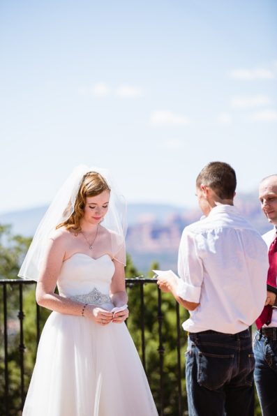 Bride while her groom reads his vows at their Sedona wedding by PMA Photography.