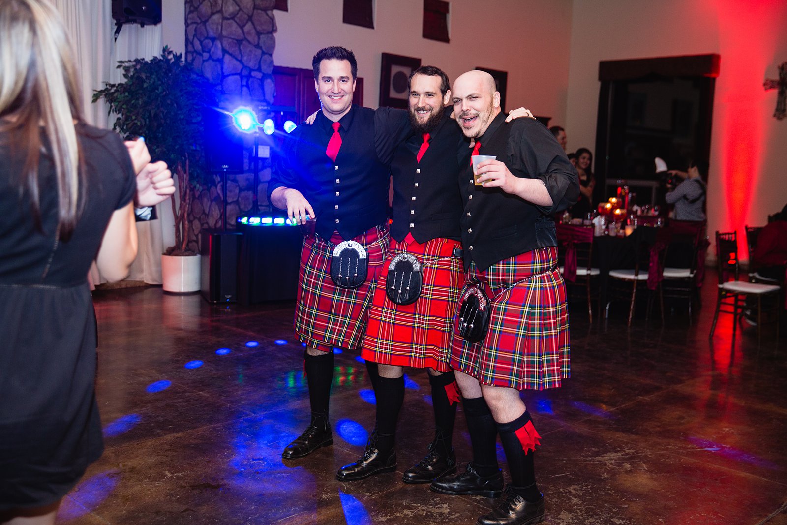 Groomsmen in kilts dance with guests at a wedding reception by PMA Photography.
