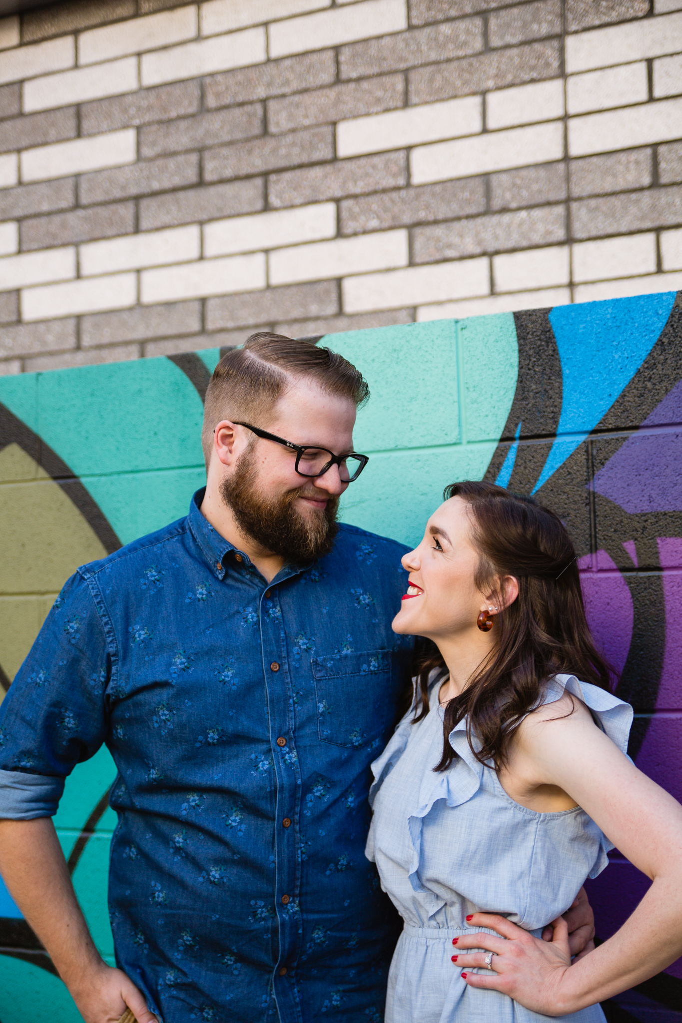 Couple looking at each other in front of art mural during their urban engagement session by Phoenix engagement photographer PMA Photography.