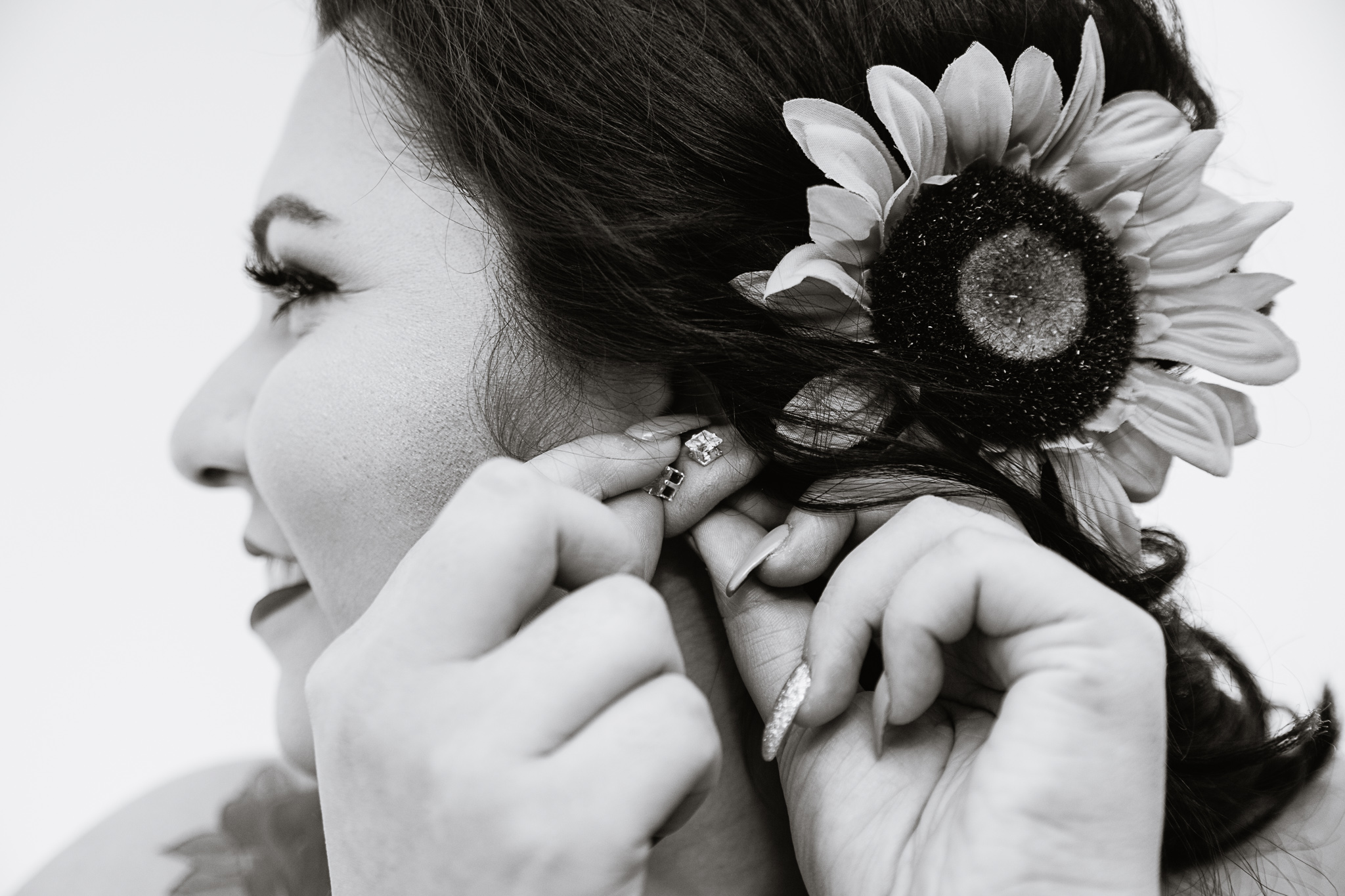 Black and white image of bride adjusting her ear rings while getting ready for her wedding by Phoenix wedding photographer PMA Photography.