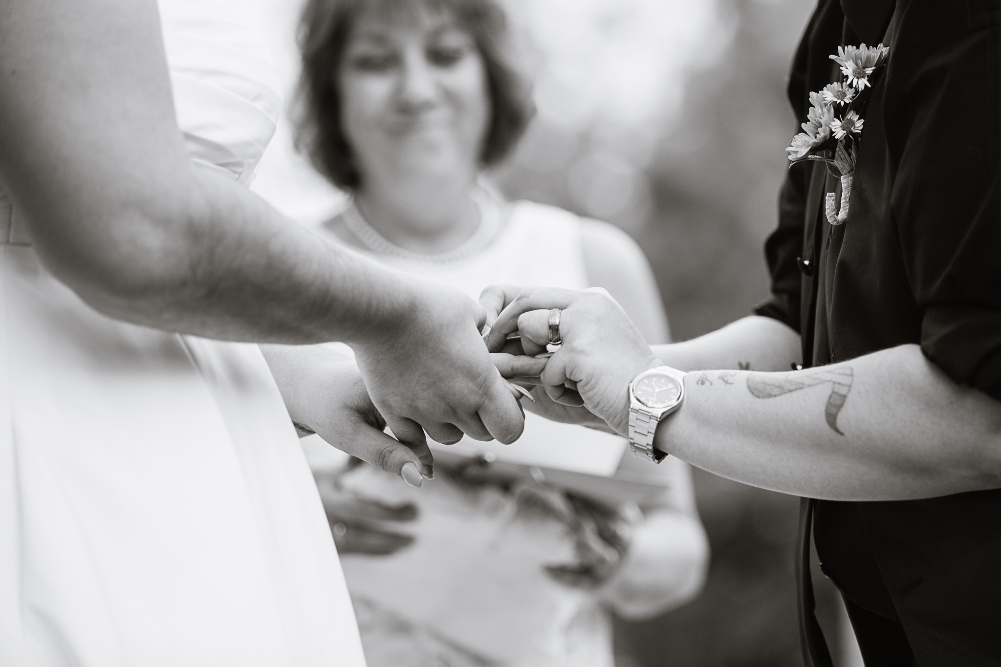 Black and white image of brides exchanging rings during LGBT wedding ceremony.