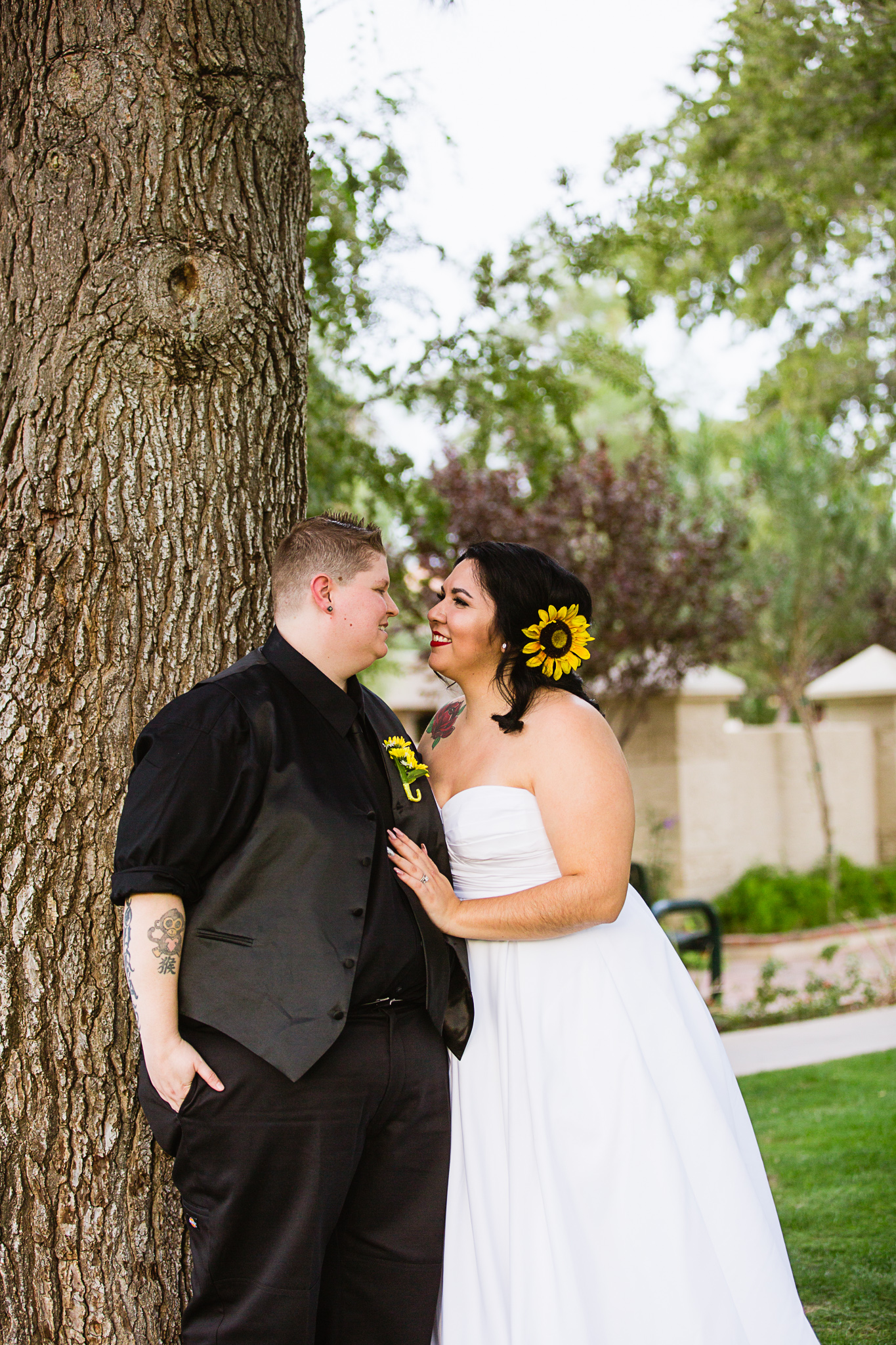 Brides share an intimate moment leaning against a tree on their wedding day by LGBT friendly wedding photographer PMA Photography.