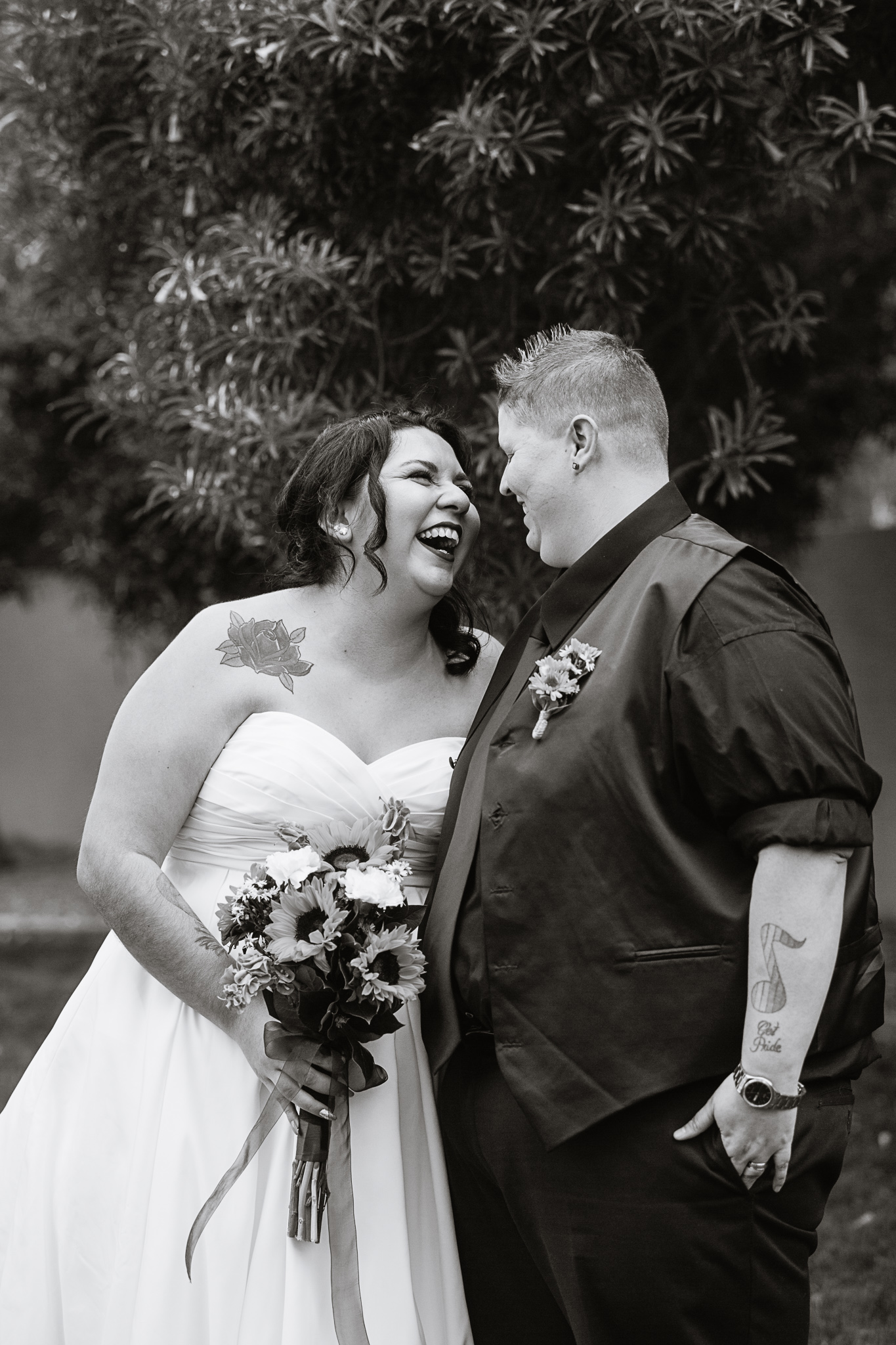 Black and white image of brides sharing a laugh on their wedding day by LGBT friendly wedding photographer PMA Photography.