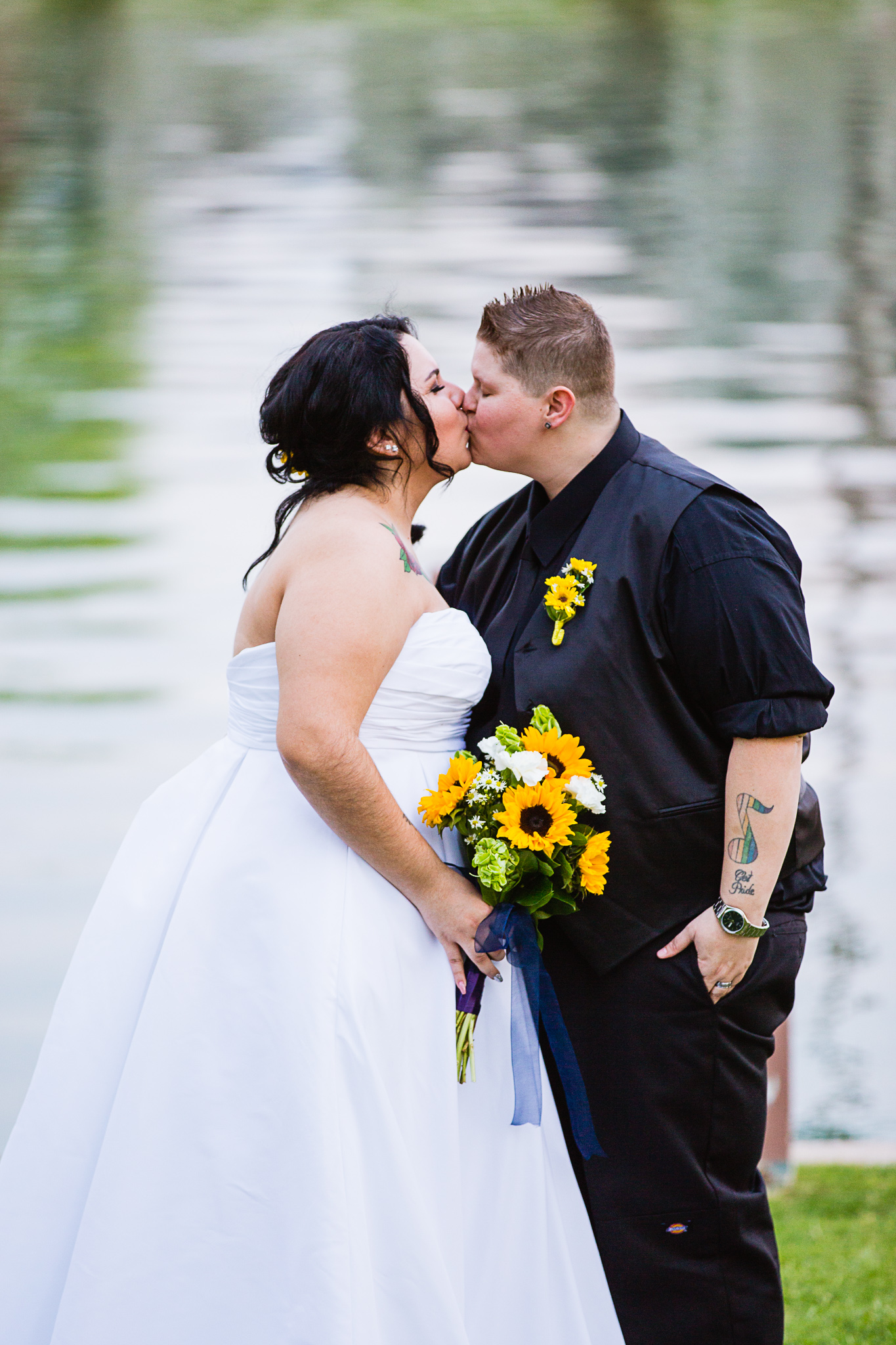Same sex couple kissing in front of a lake on their wedding day by Phoenix wedding photographers PMA Photography.