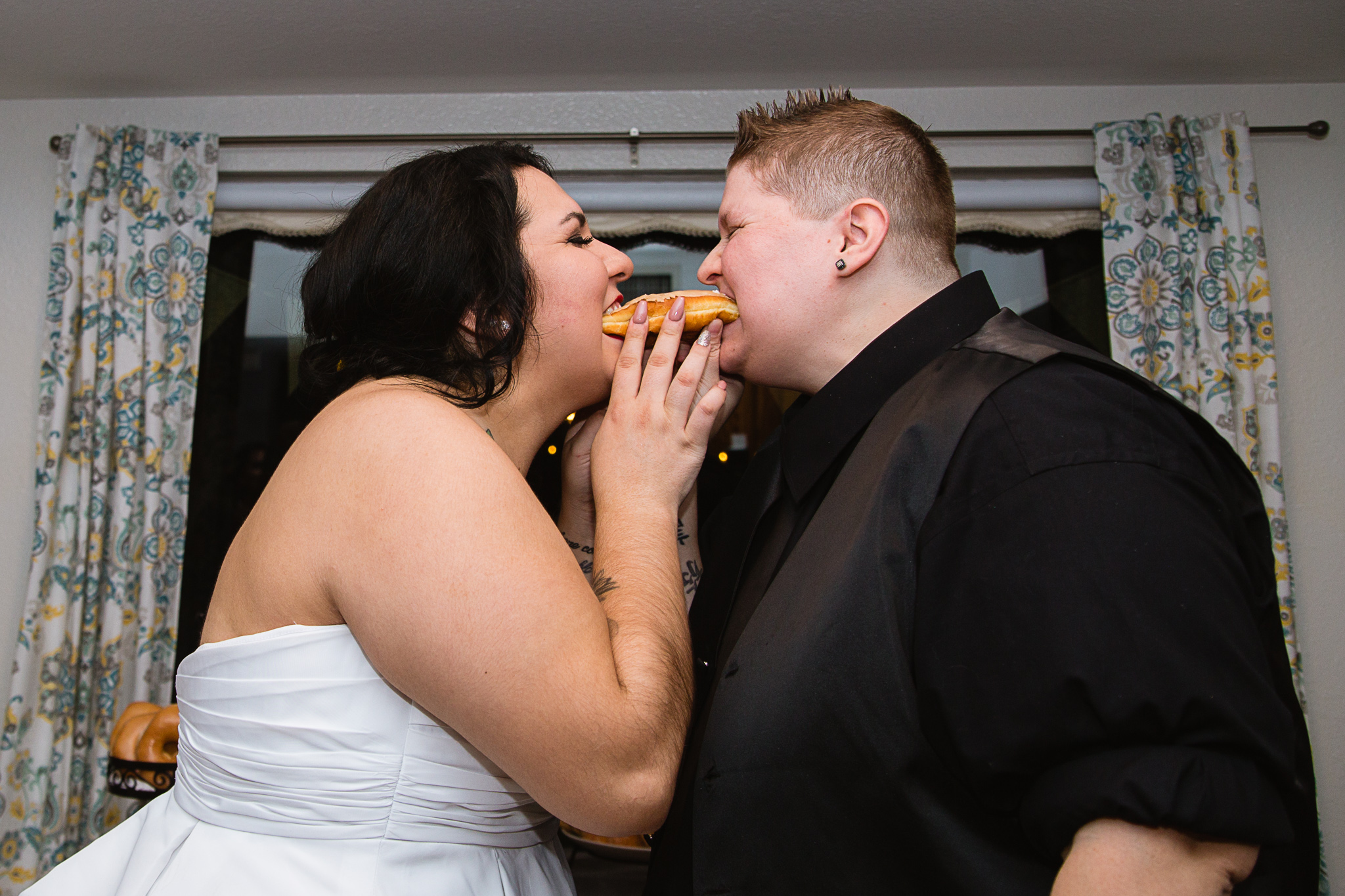 Same sex couple share a long john donut instead of cake on their wedding night.