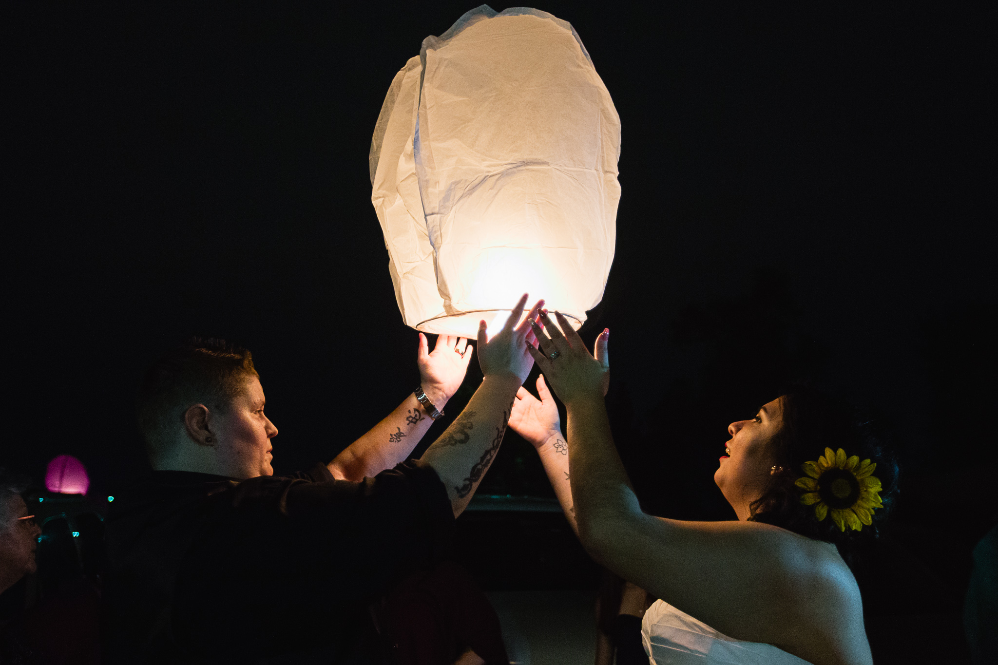 Brides light paper lanterns with guests as part of their reception to remember lost loved ones.