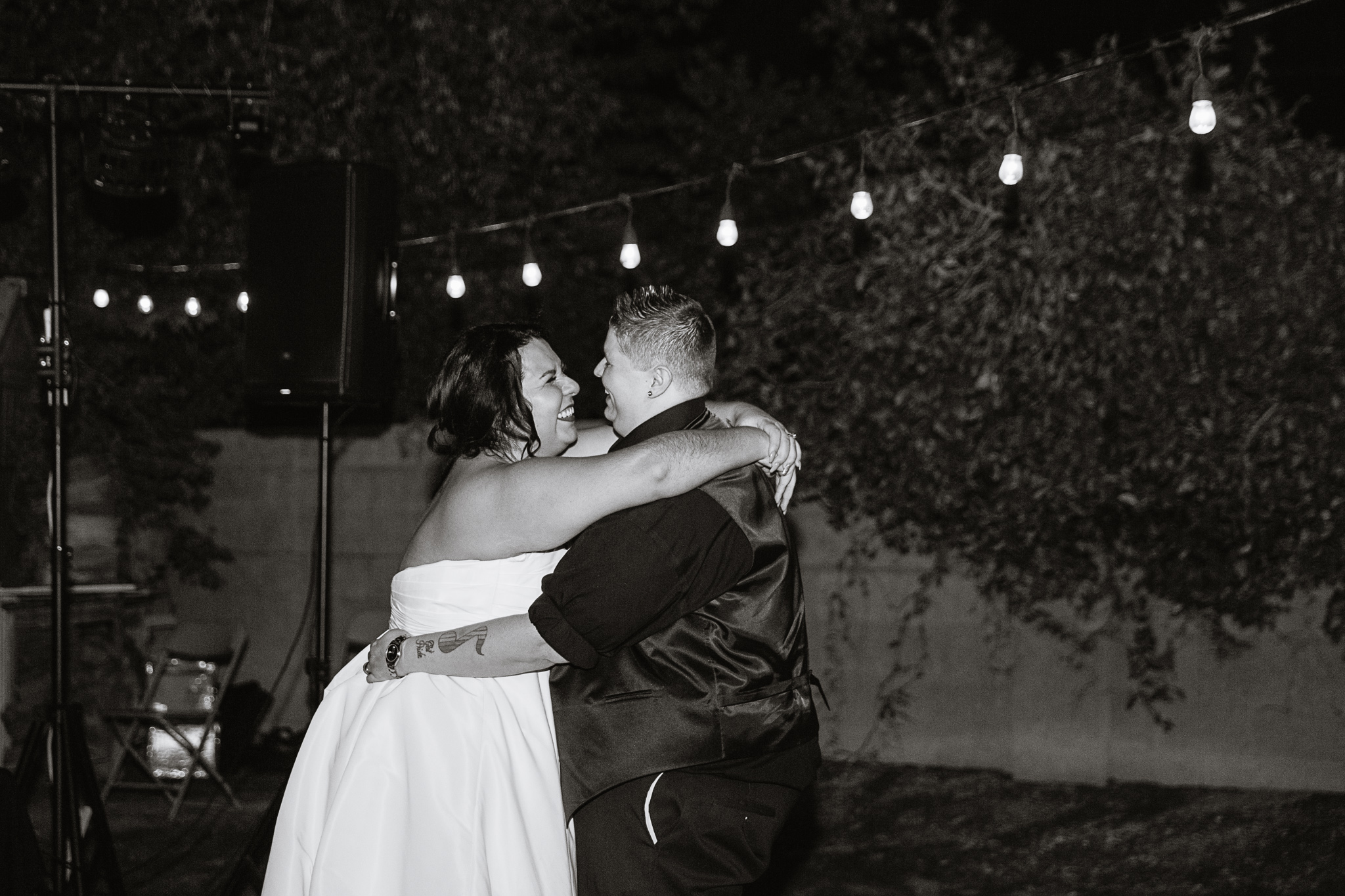 Black and white image of Same sex couple share their first dance at their garden backyard wedding by Phoenix wedding photographers PMA Photography.