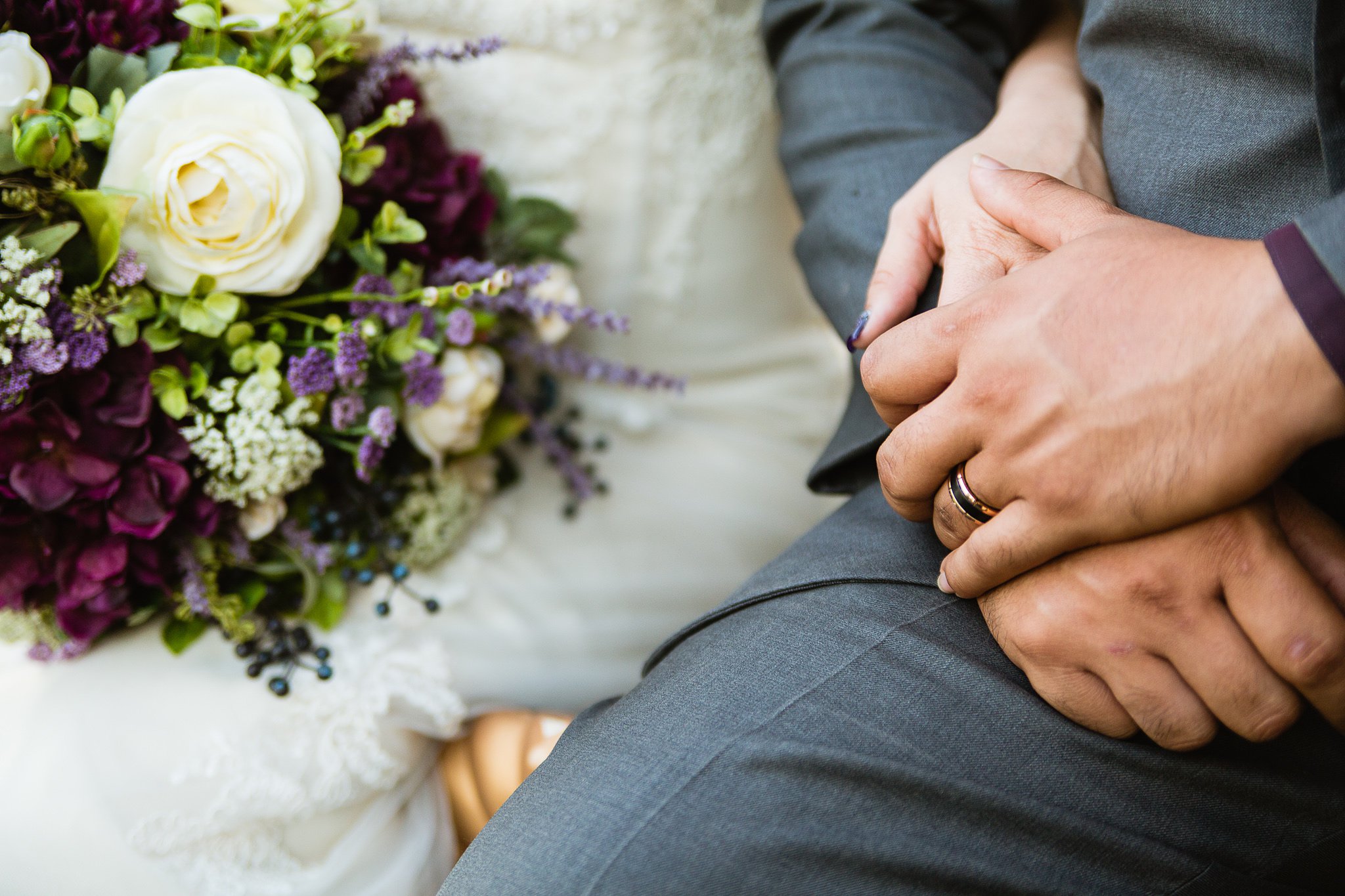 Close up image of a groom's wedding band holding his bride's hand by Arizona wedding photographer PMA Photography.