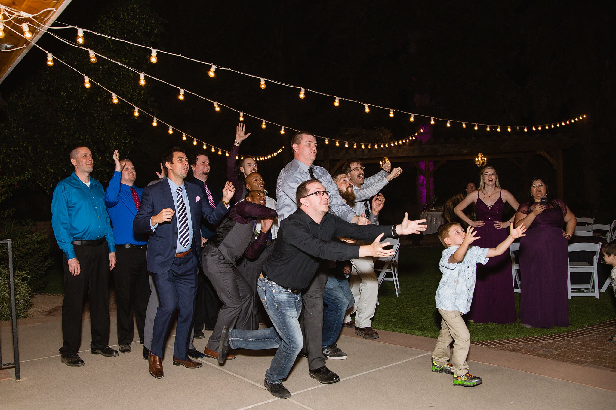 Guests catching garter at wedding reception by wedding photographer PMA Photography.