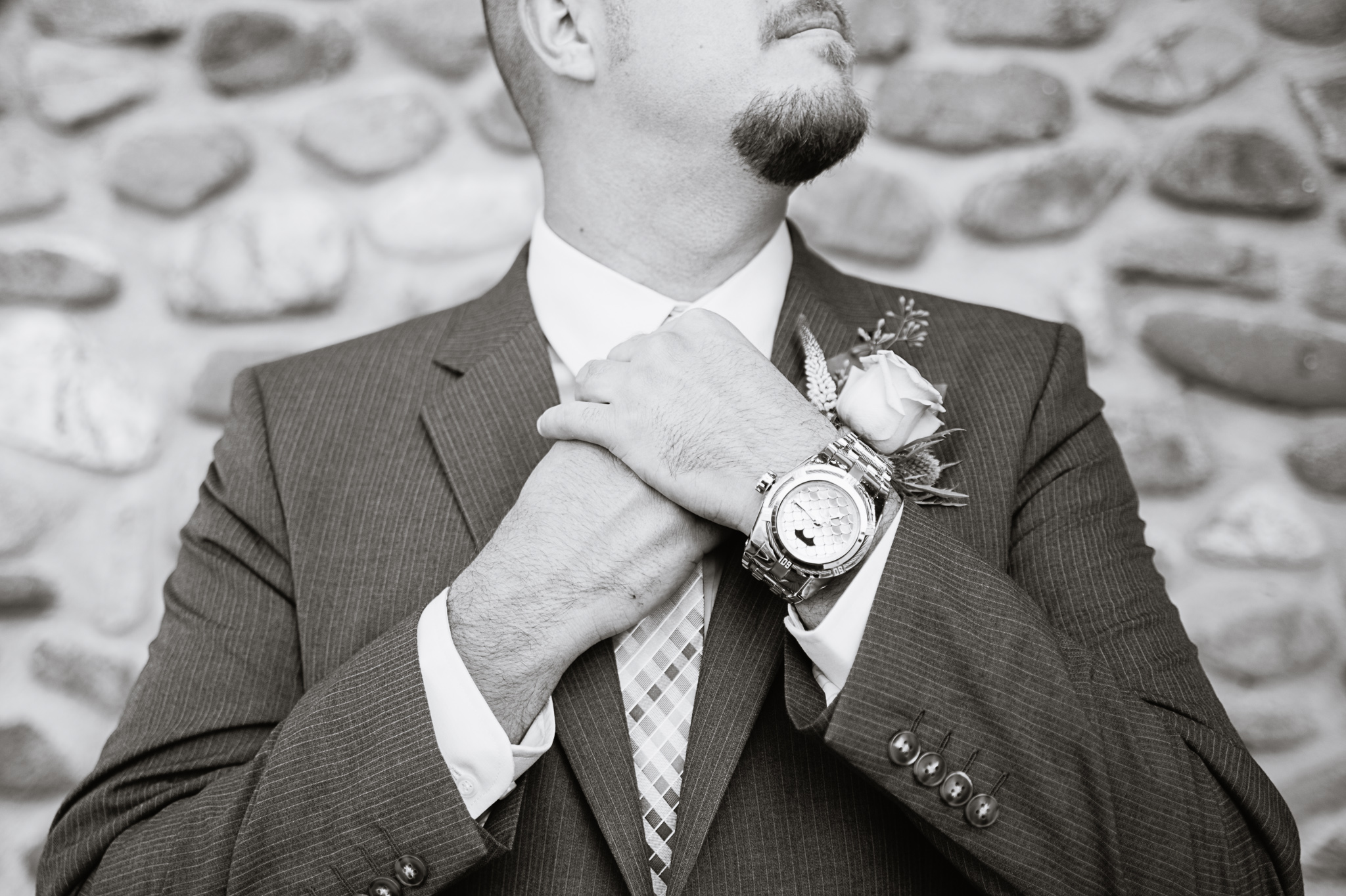 Black and white image groom adjusting his tie while getting ready for his wedding day by Arizona wedding photographer PMA Photography.