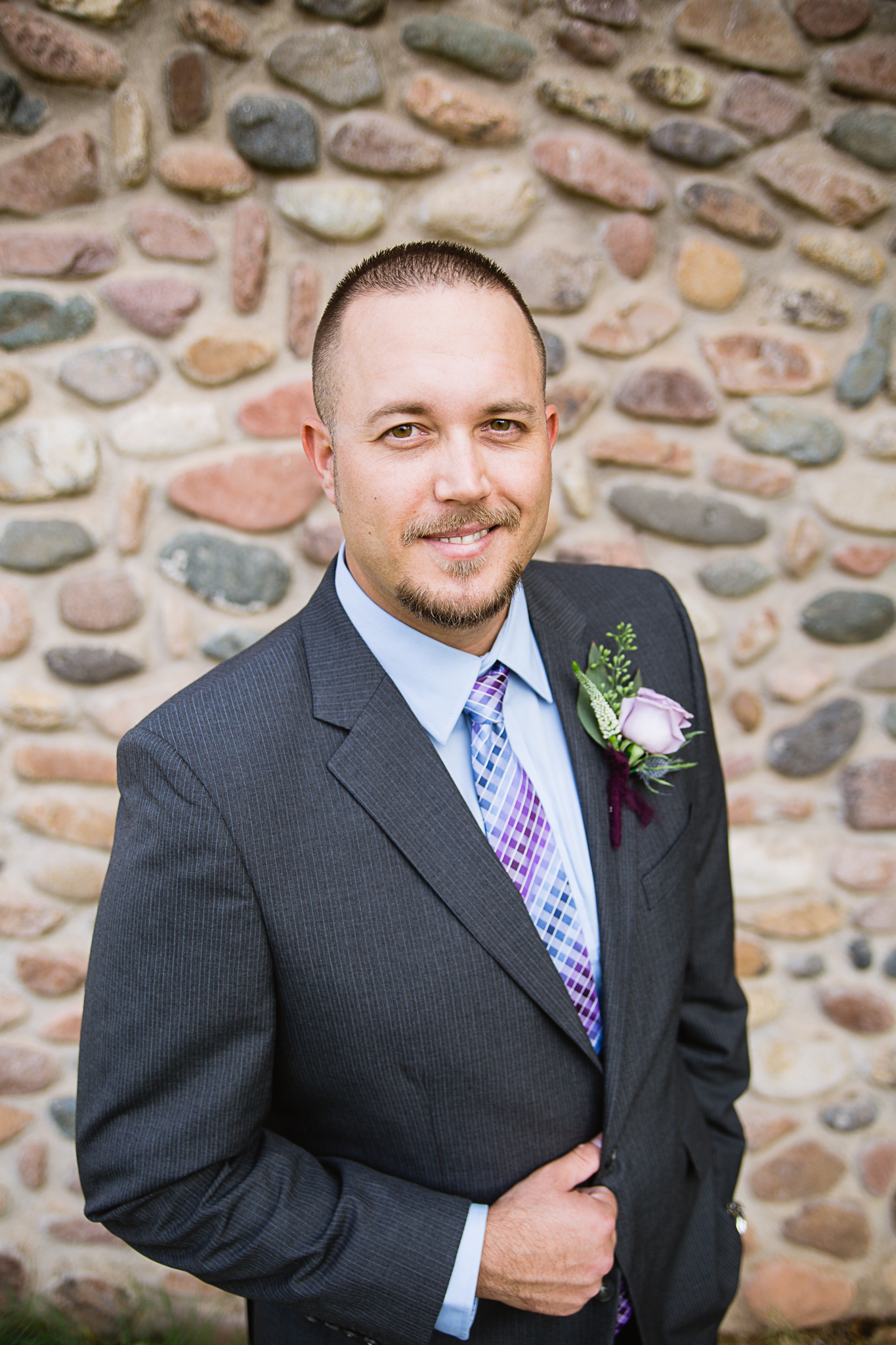 Groom in grey suit with dusty blue and lavender accents by wedding photographer PMA Photography.