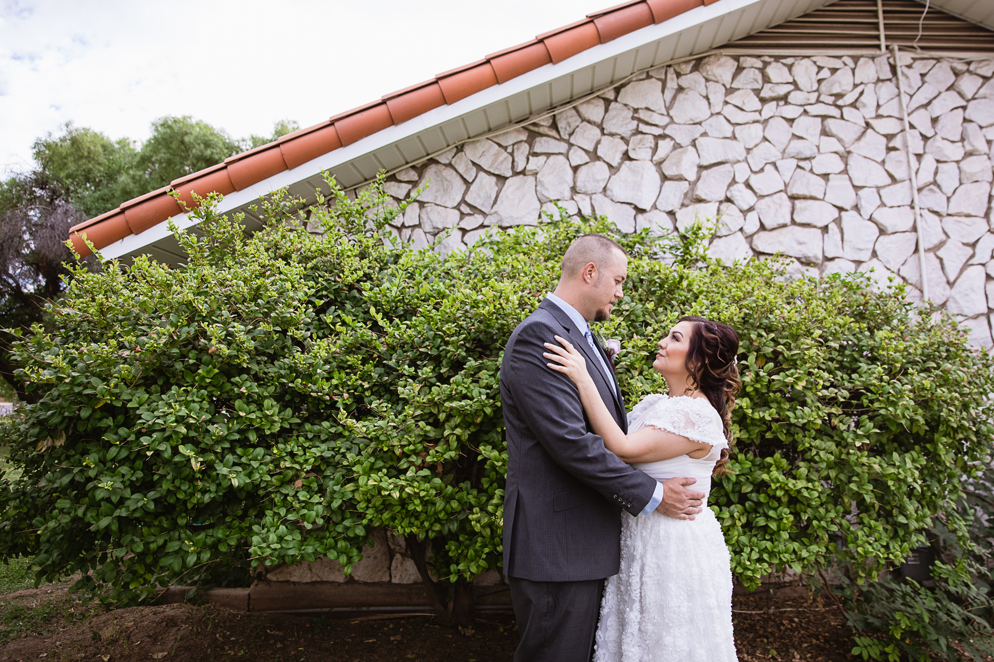 Bride and groom look at each other in front of a garden at their backyard wedding by PMA Photography.