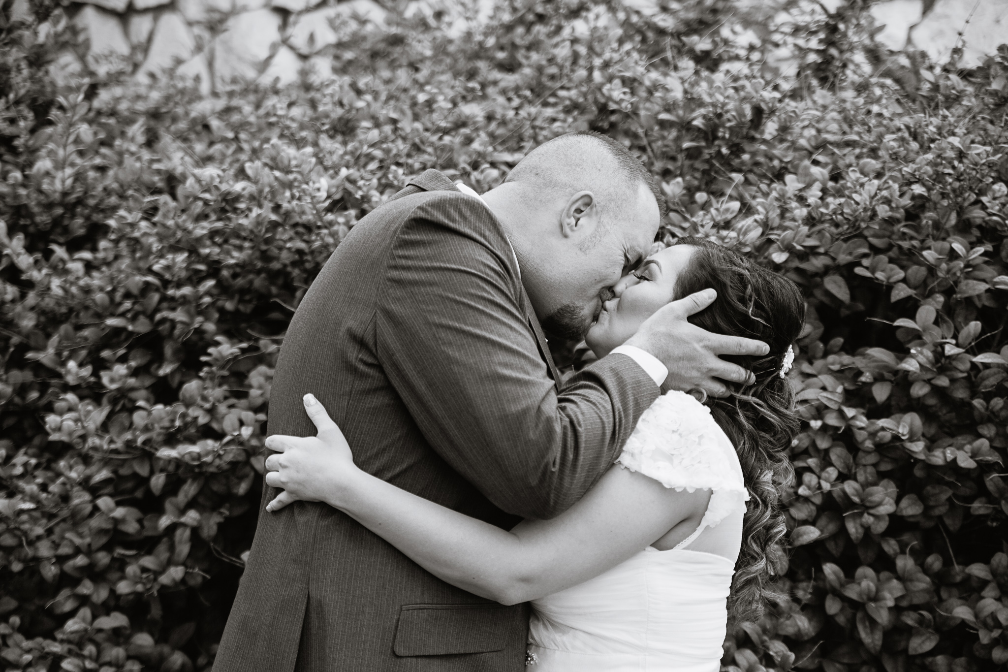 Black and white image of bride and groom kissing on their wedding day by PMA Photography.