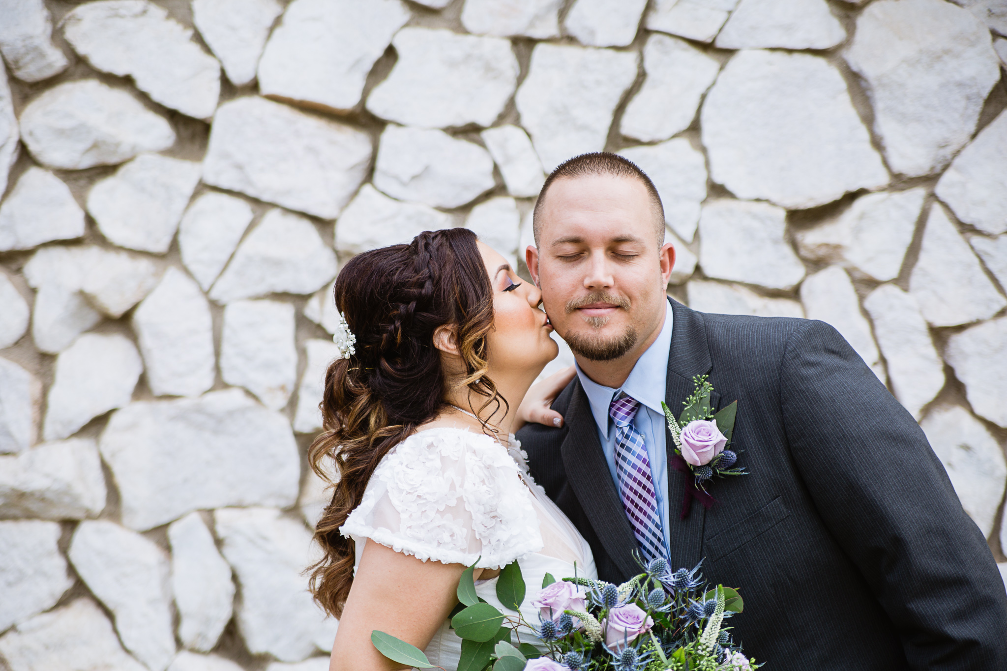 Bride kisses groom's cheek on their wedding day by Arizona wedding photographer PMA Photography.