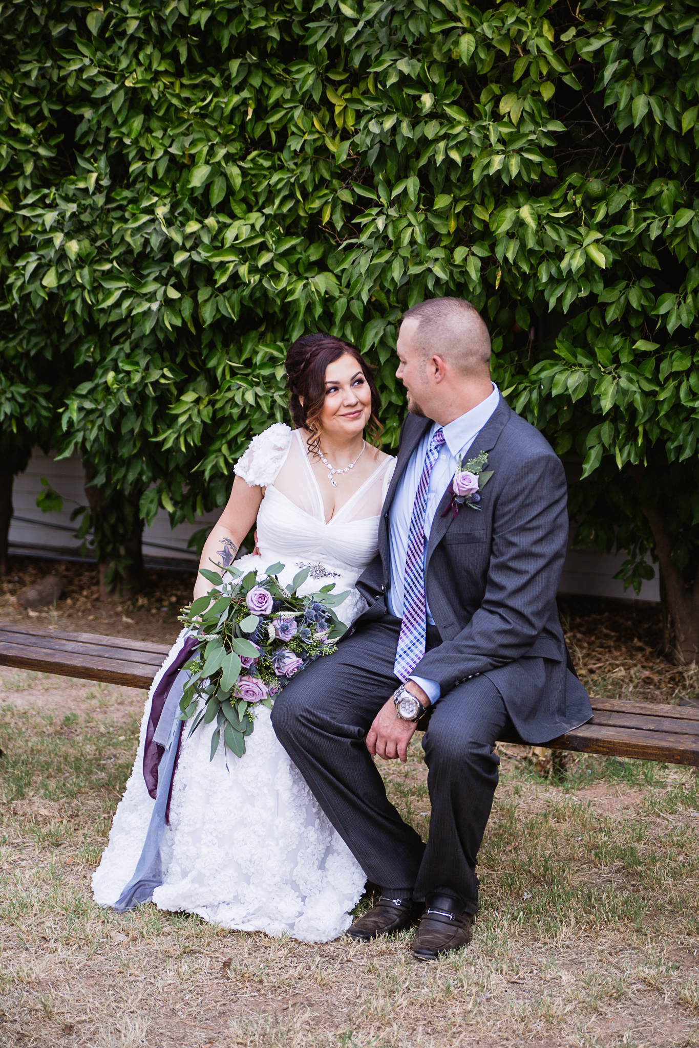 Bride and groom look lovingly at each other on a bench by Arizona wedding photographer PMA Photography.