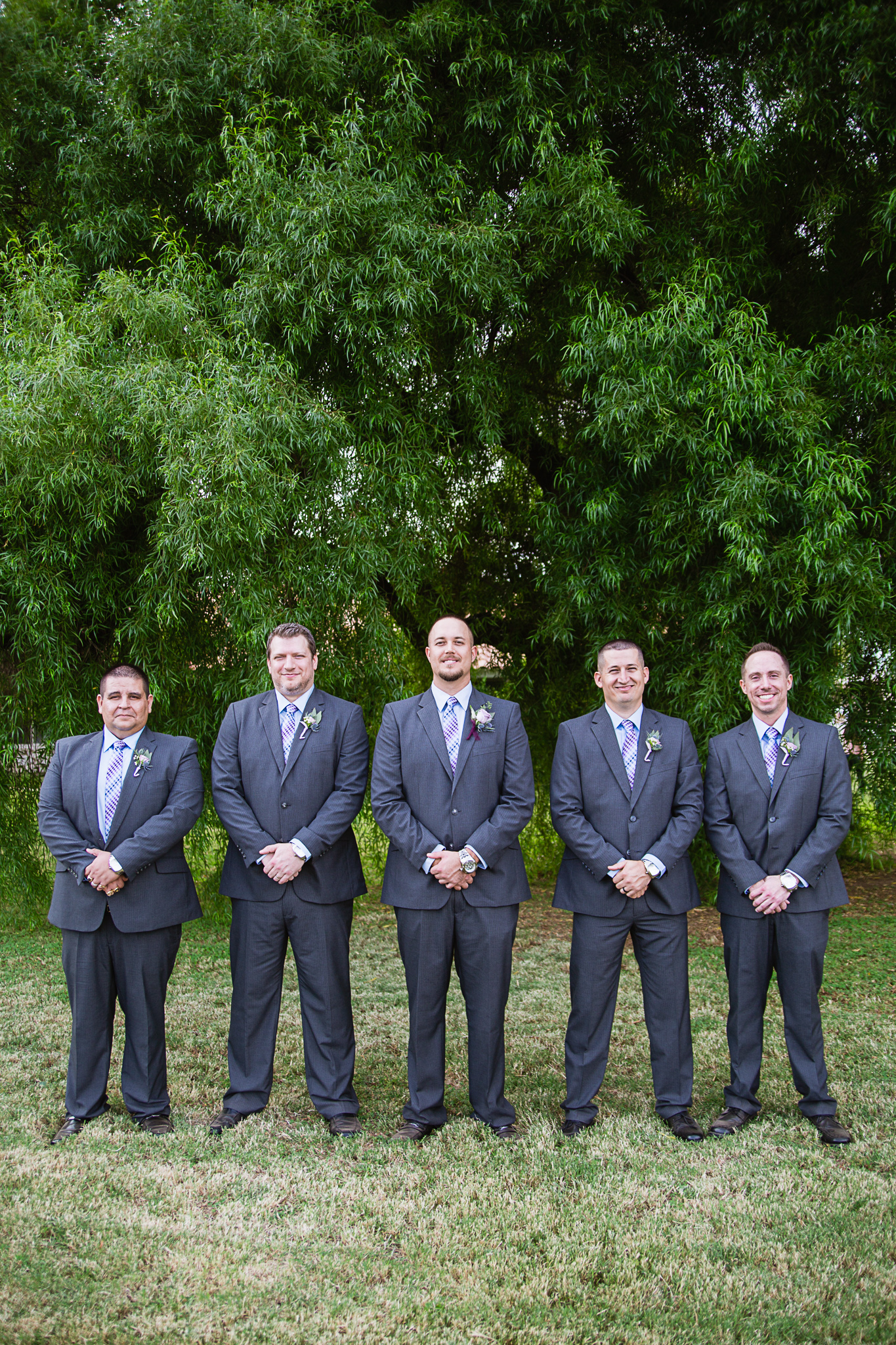Groom and groomsmen in grey suits with dusty blue and lavender accents by Phoenix wedding photographer PMA Photography.