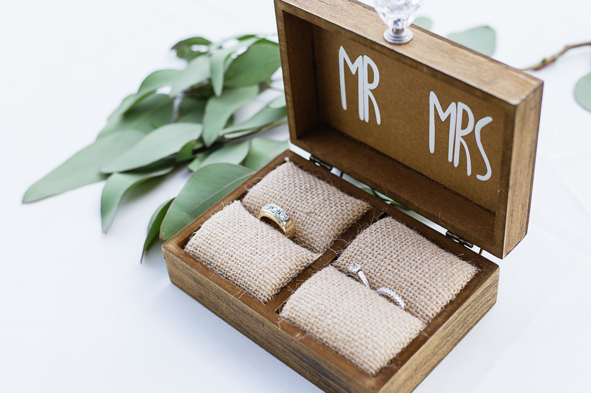 Bride and groom's wedding rings in a rustic Mr. and Mrs. box by PMA Photography.