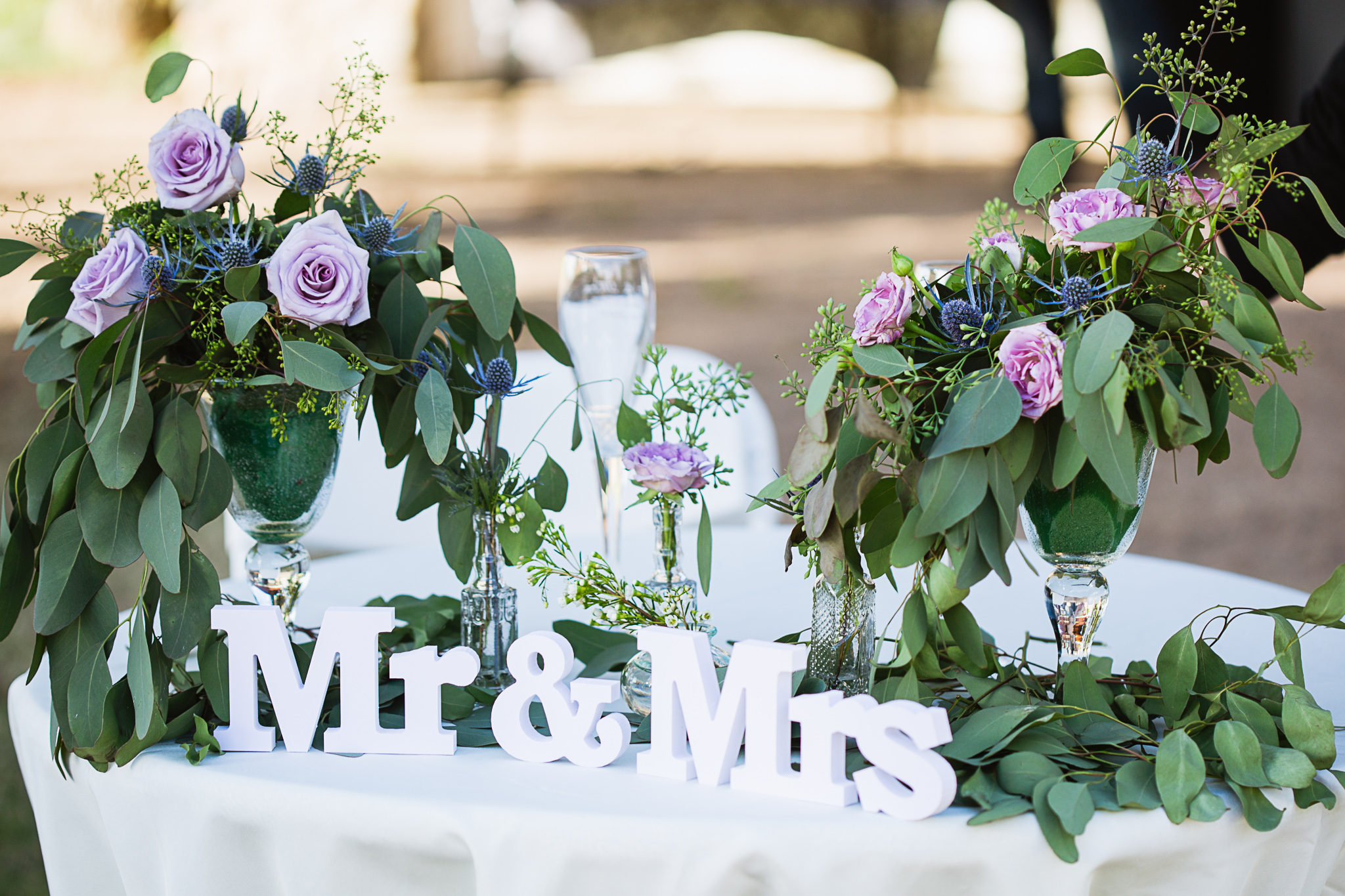 Sweetheart table decorated with eucalyptus and lavender roses by PMA Photography.