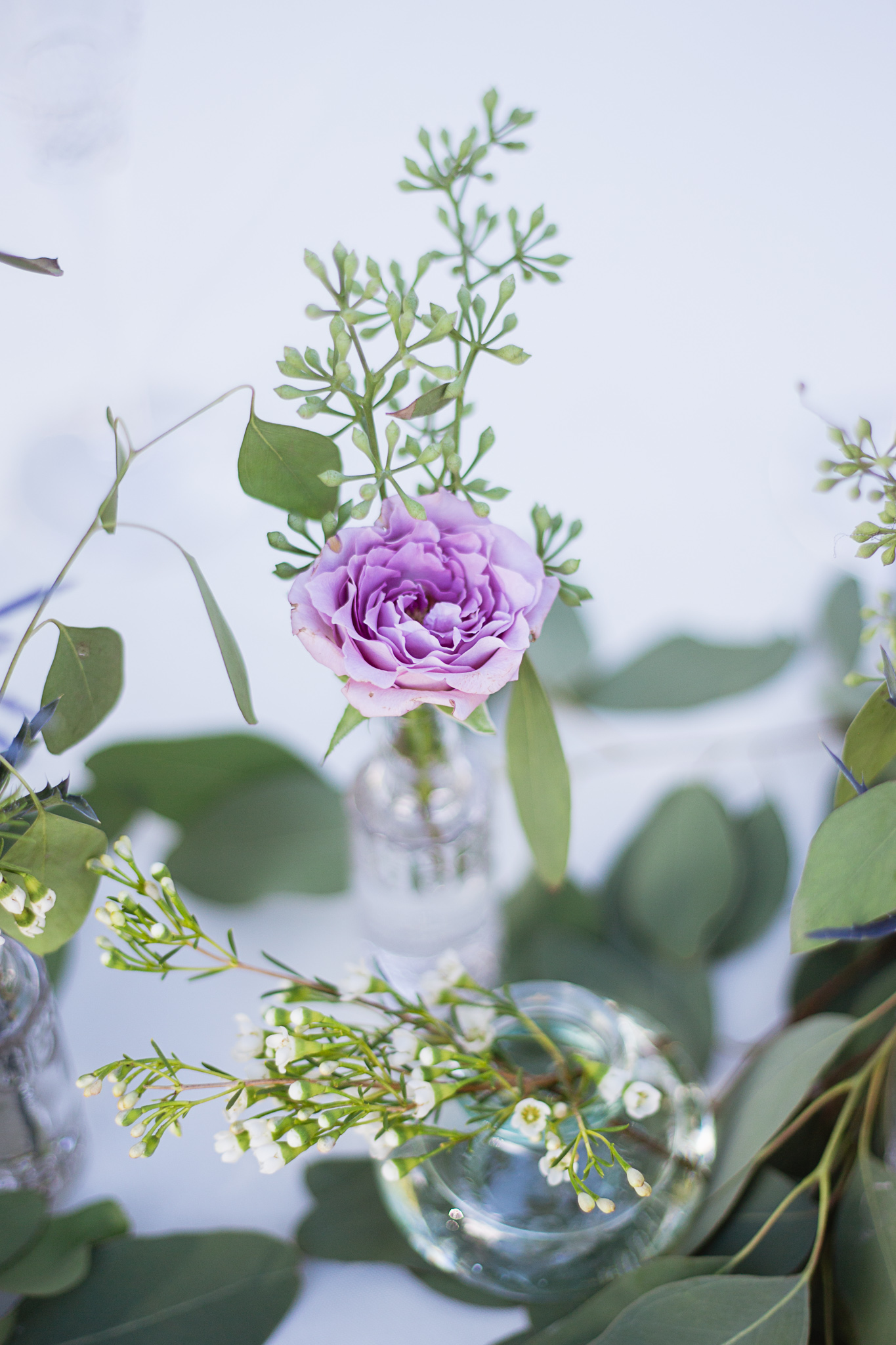 Lavender rose and eucalyptus in vintage bottles decorating a sweetheart table by PMA Photography.