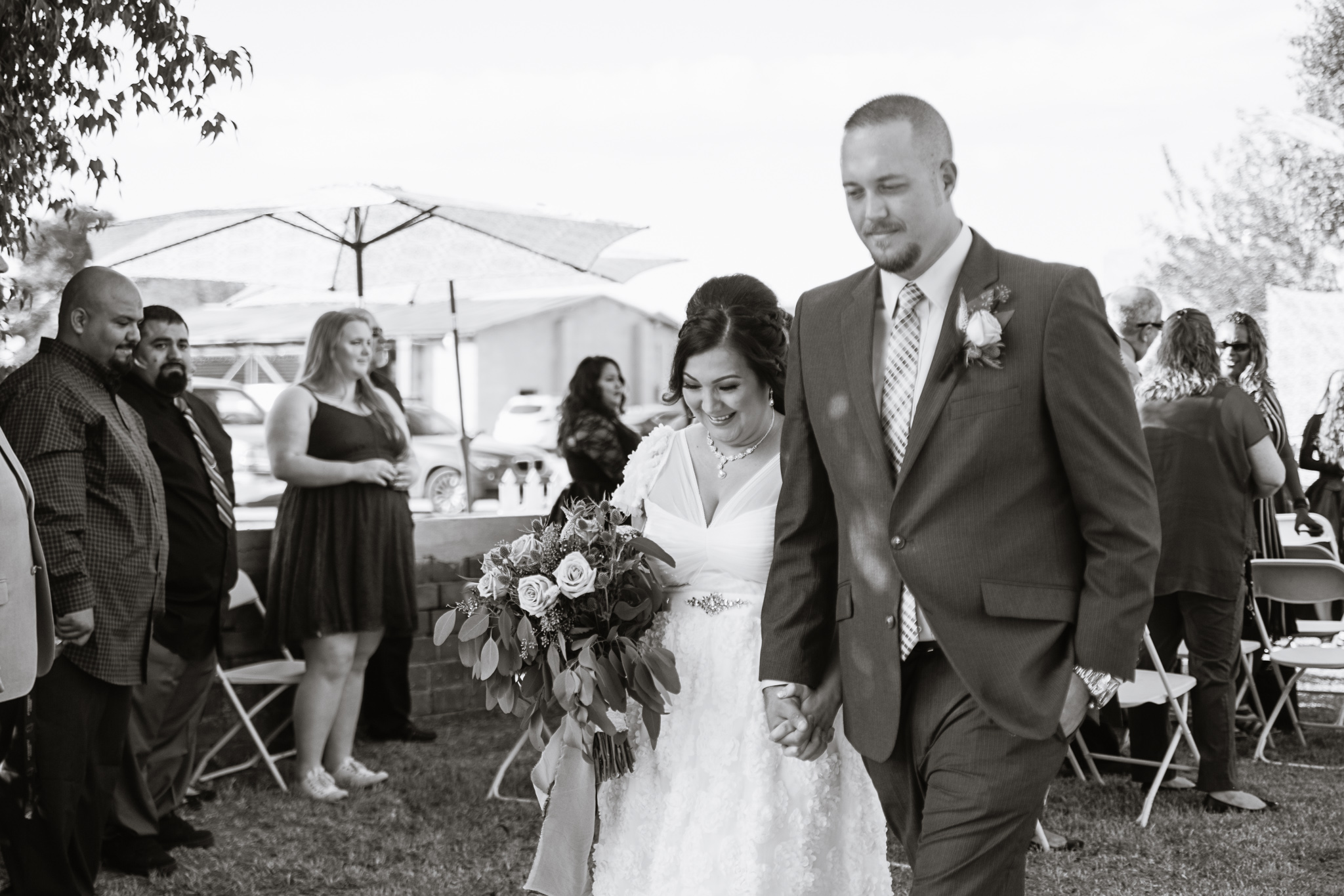 Bride smiling as she walks back down the aisle with her groom by PMA Photography.