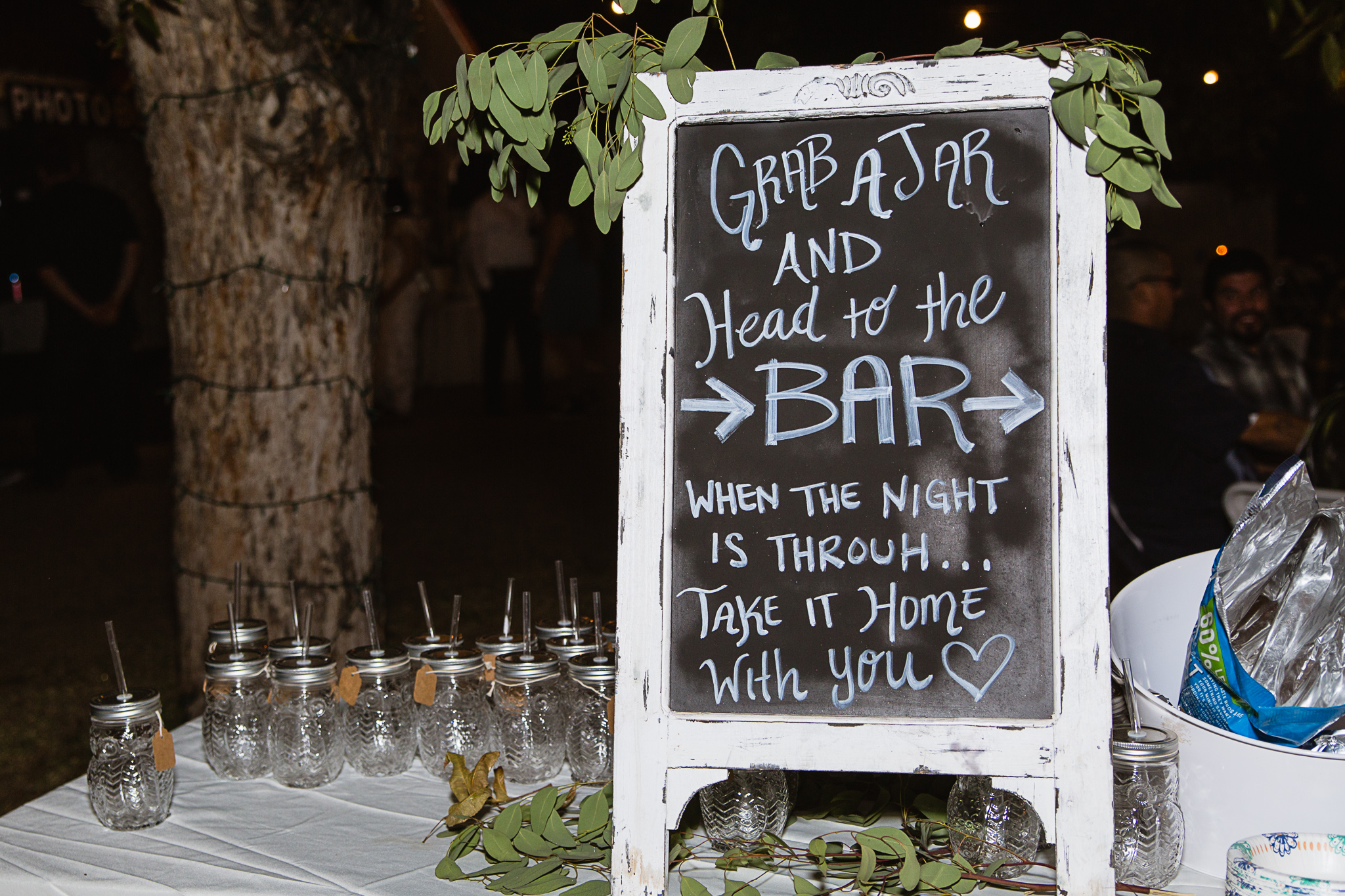 Mason jar wedding favors with a "Grab a jar and head to the bar" rustic sign by PMA Photography.