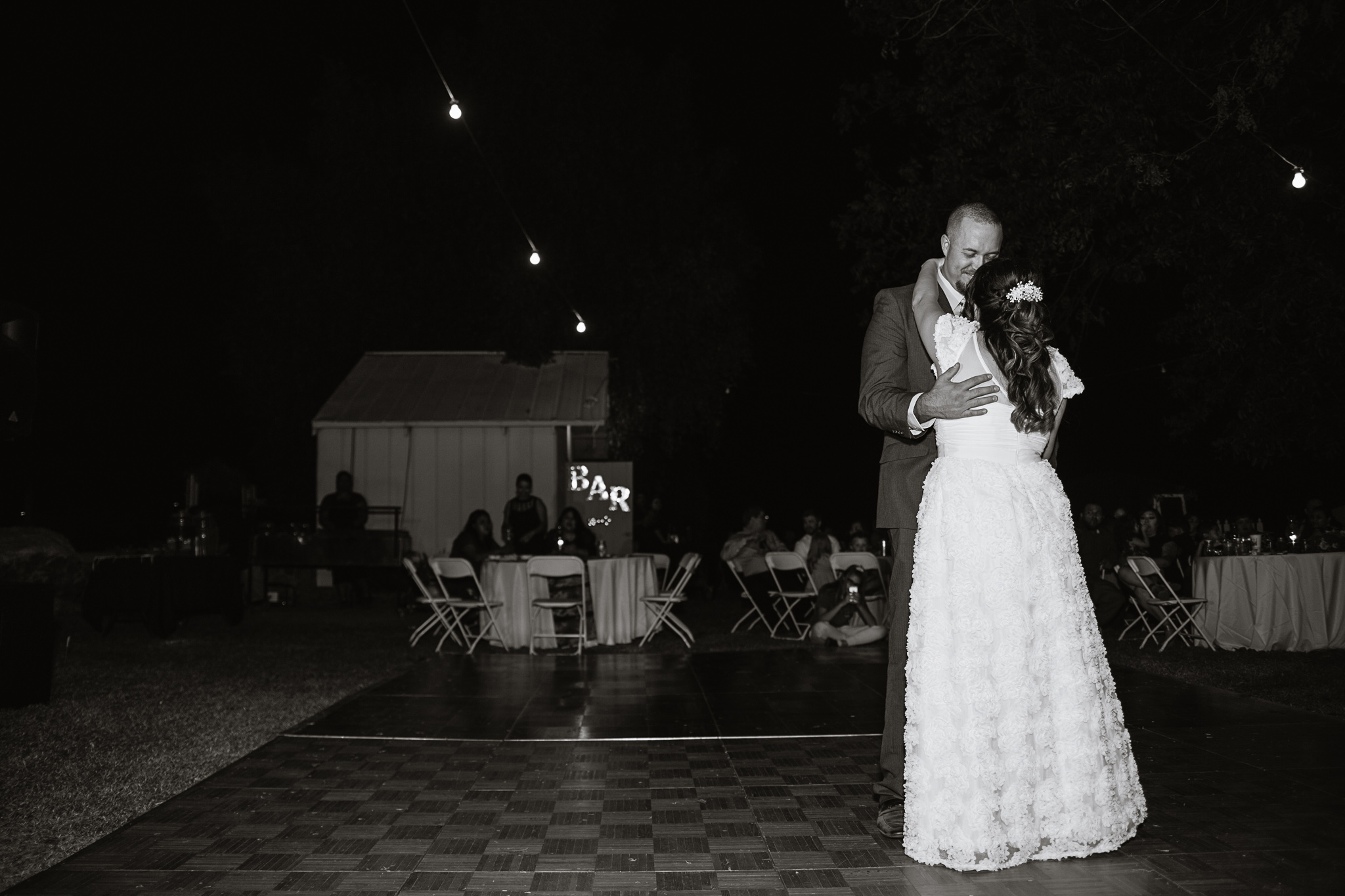 Black and white image of couple sharing their first dance at their wedding reception by PMA Photography.