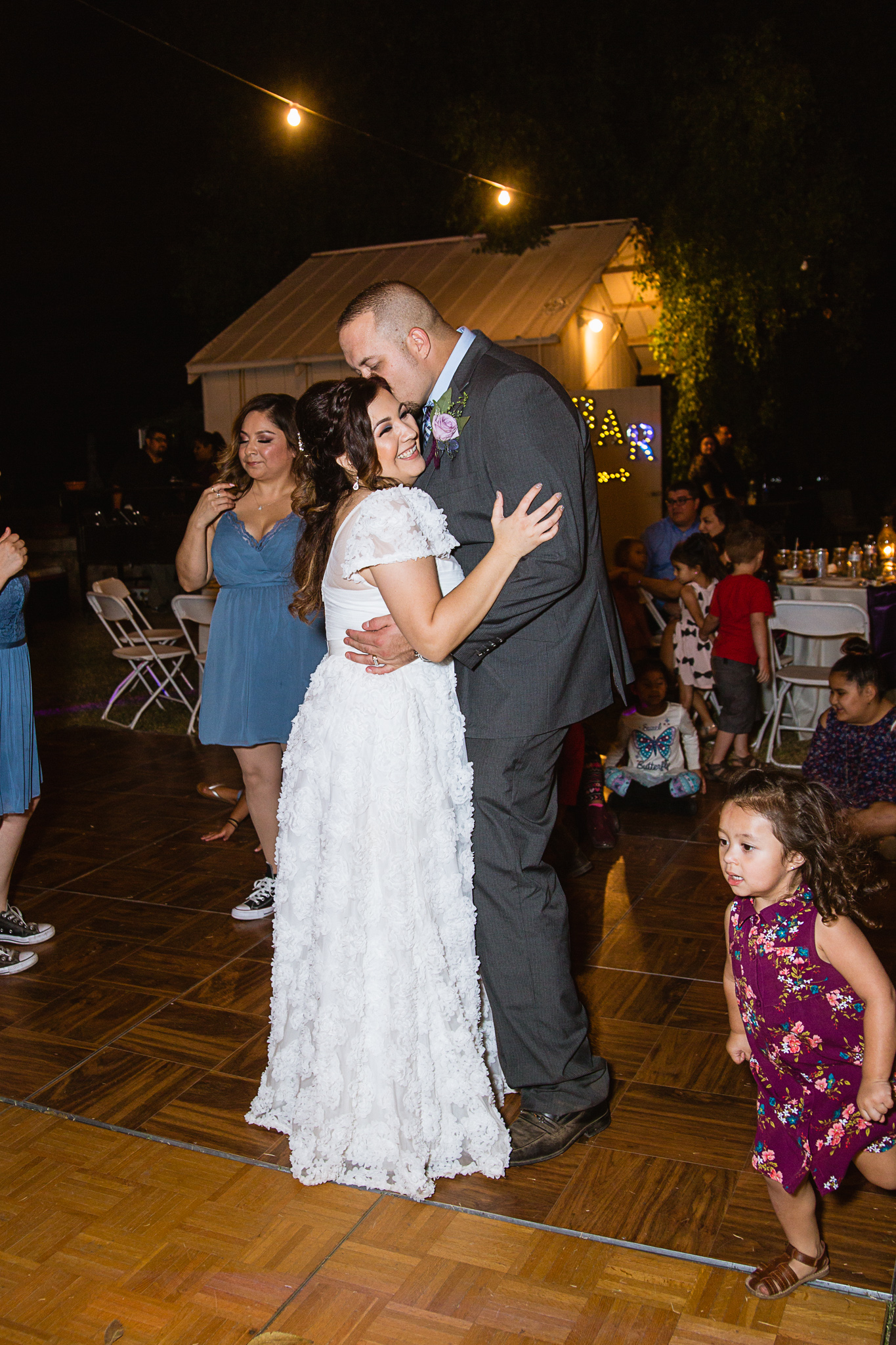 Bride and groom dance together with guests at the wedding reception by PMA Photography.
