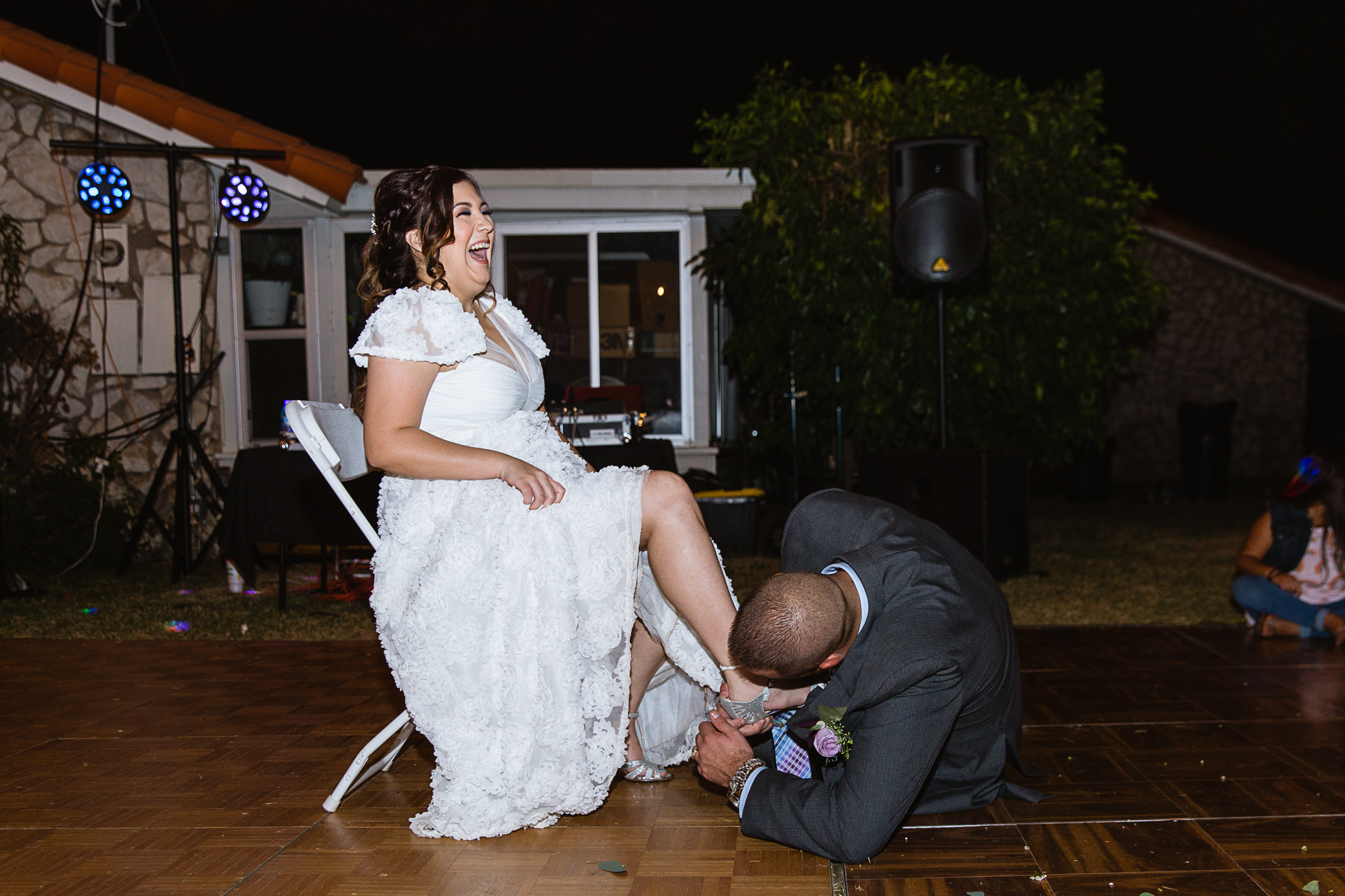 Bride laughs as groom goes under her dress to get the garter by PMA Photography.