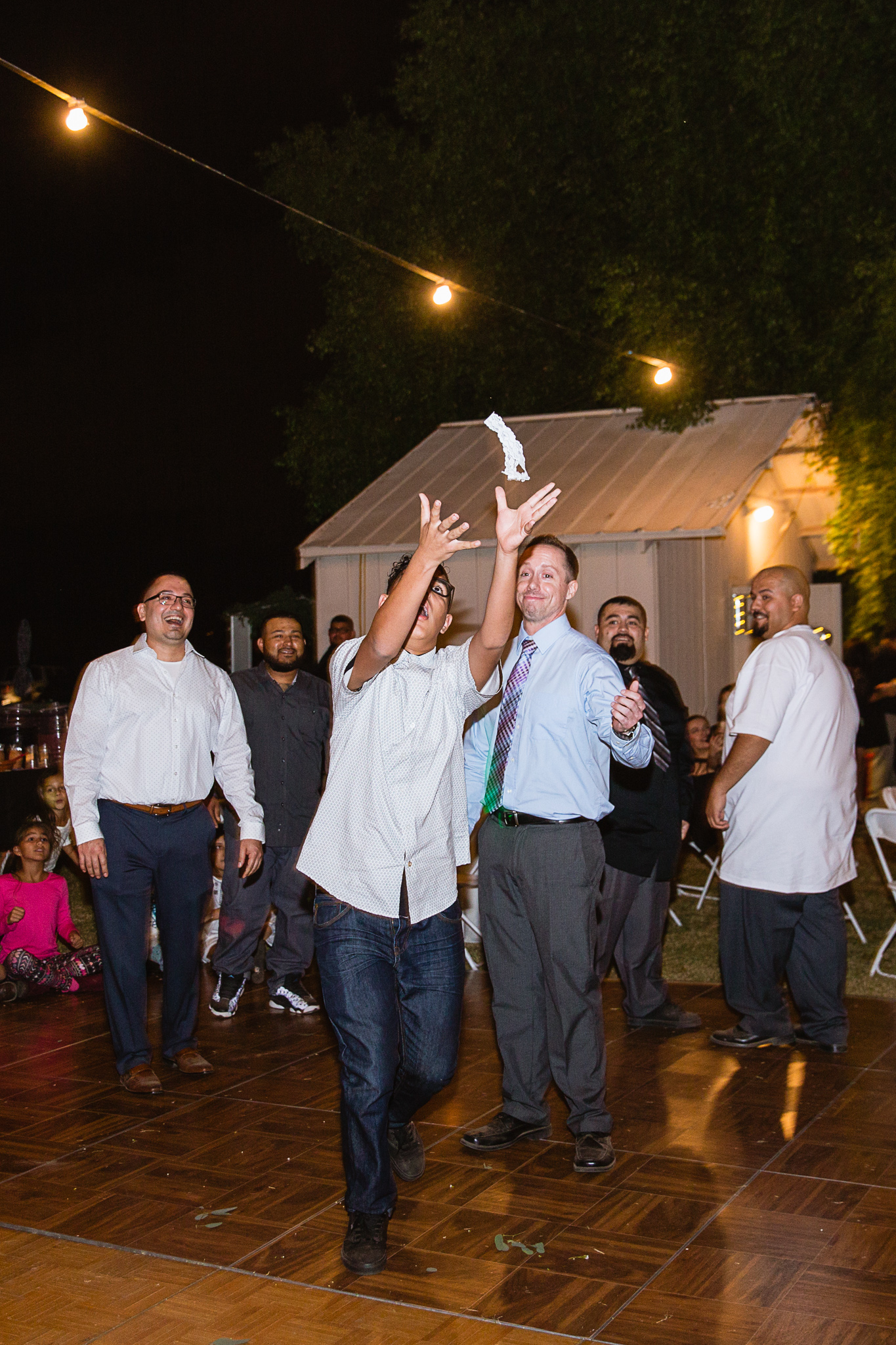 Garter toss at a backyard wedding reception by PMA Photography.