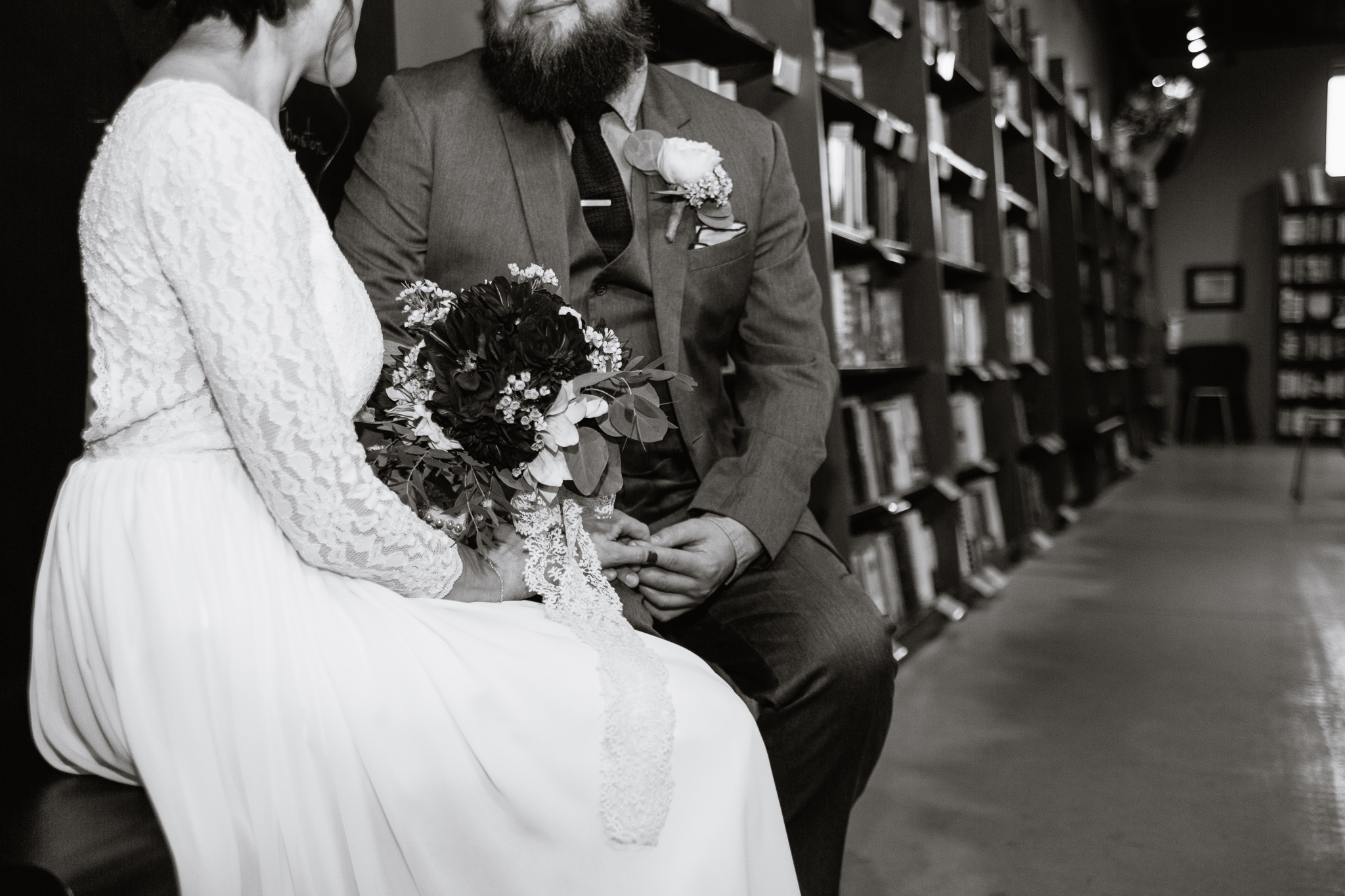 Black and white image of bride and groom with bridal bouquet in Changing Hand bookstore for their book themed wedding in Phoenix Arizona