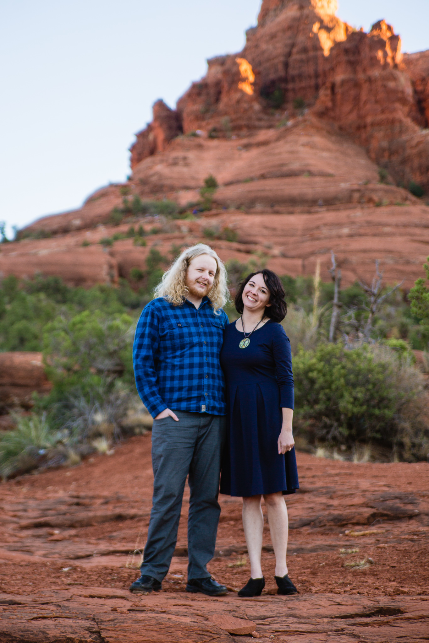 Couple posing in front of Bell Rock during their Sedona engagement session by PMA Photography.
