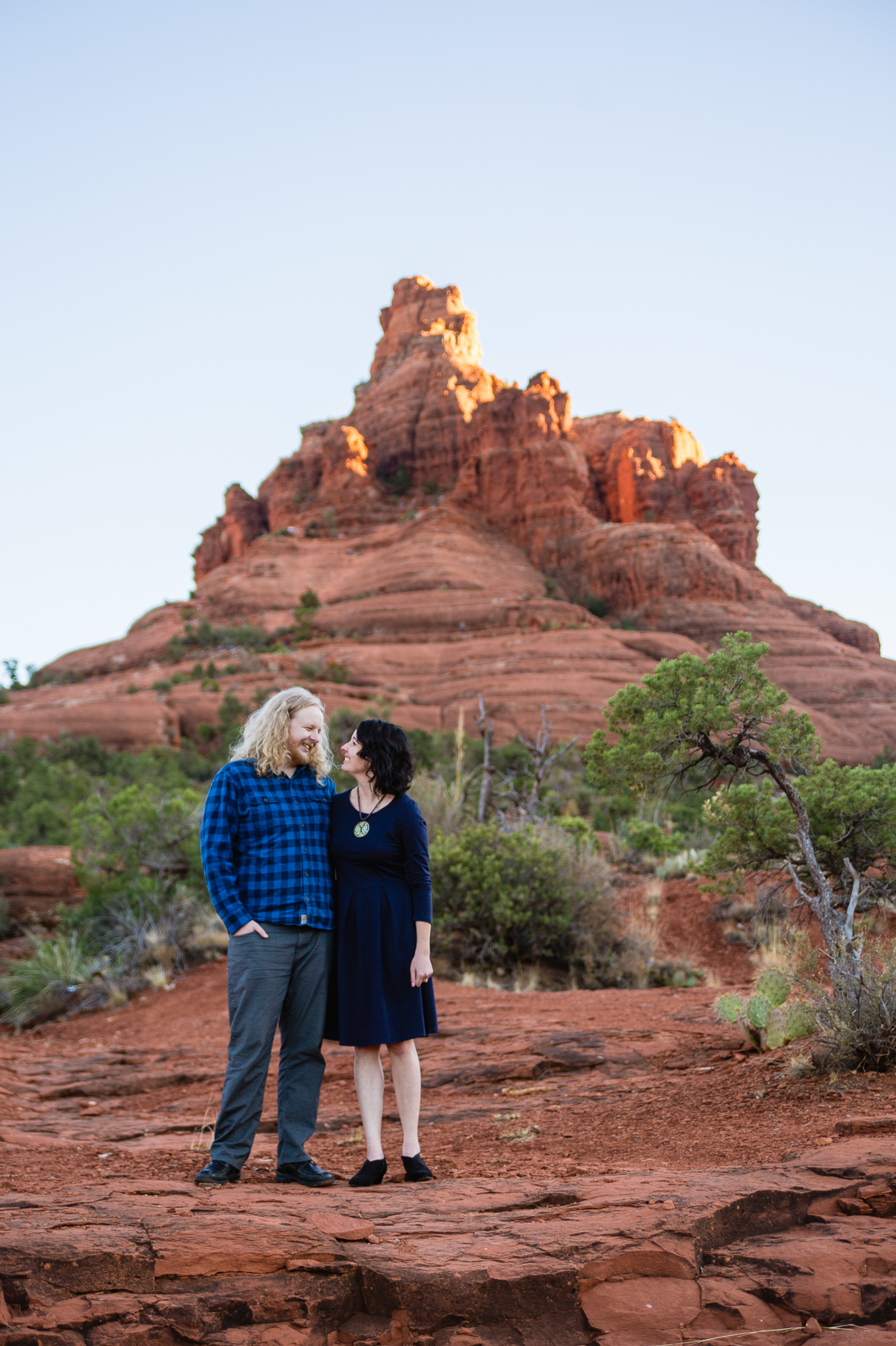 Couple looking at each other in front of Bell Rock during their Sedona engagement session by PMA Photography.
