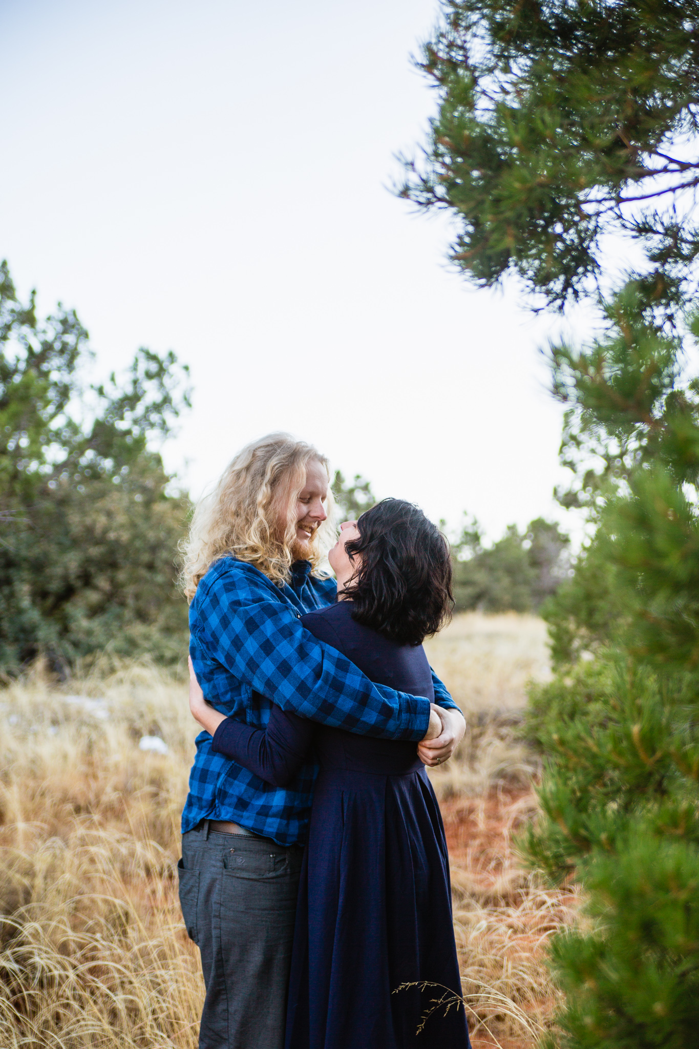Couple looking at each other in navy and grey outfits during engagement session in Sedona Arizona by PMA Photography.