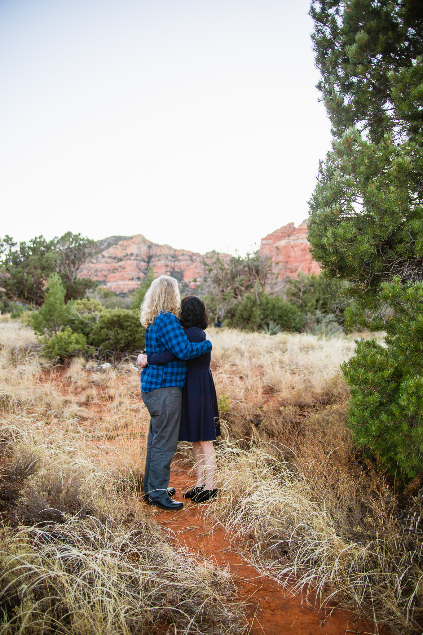 Couple admiring the red rocks of Sedona in navy and grey outfits during engagement session by PMA Photography.