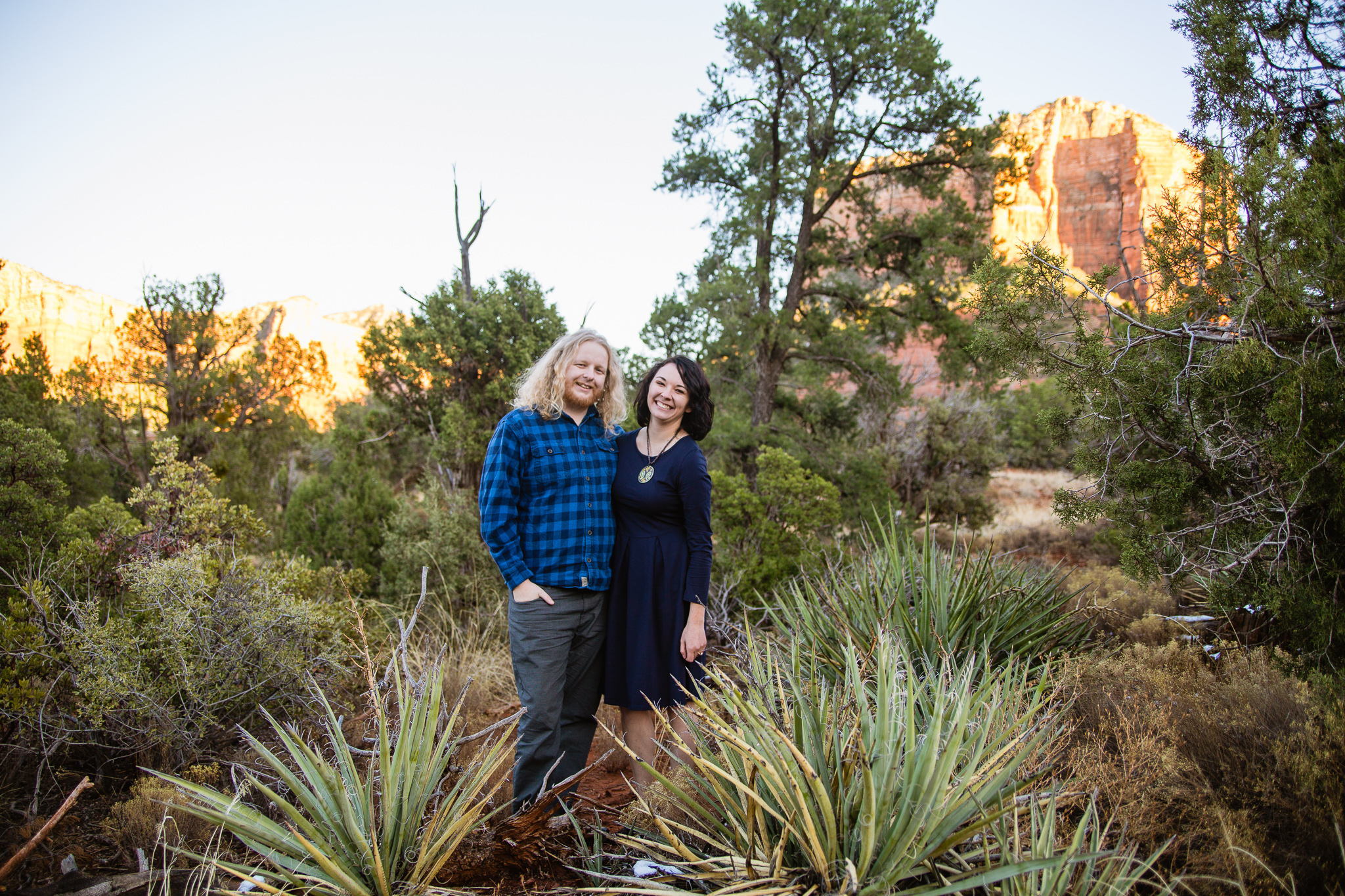 Couple surrounded by green plants and speckles of snow at Sedona engagement session by PMA Photography.