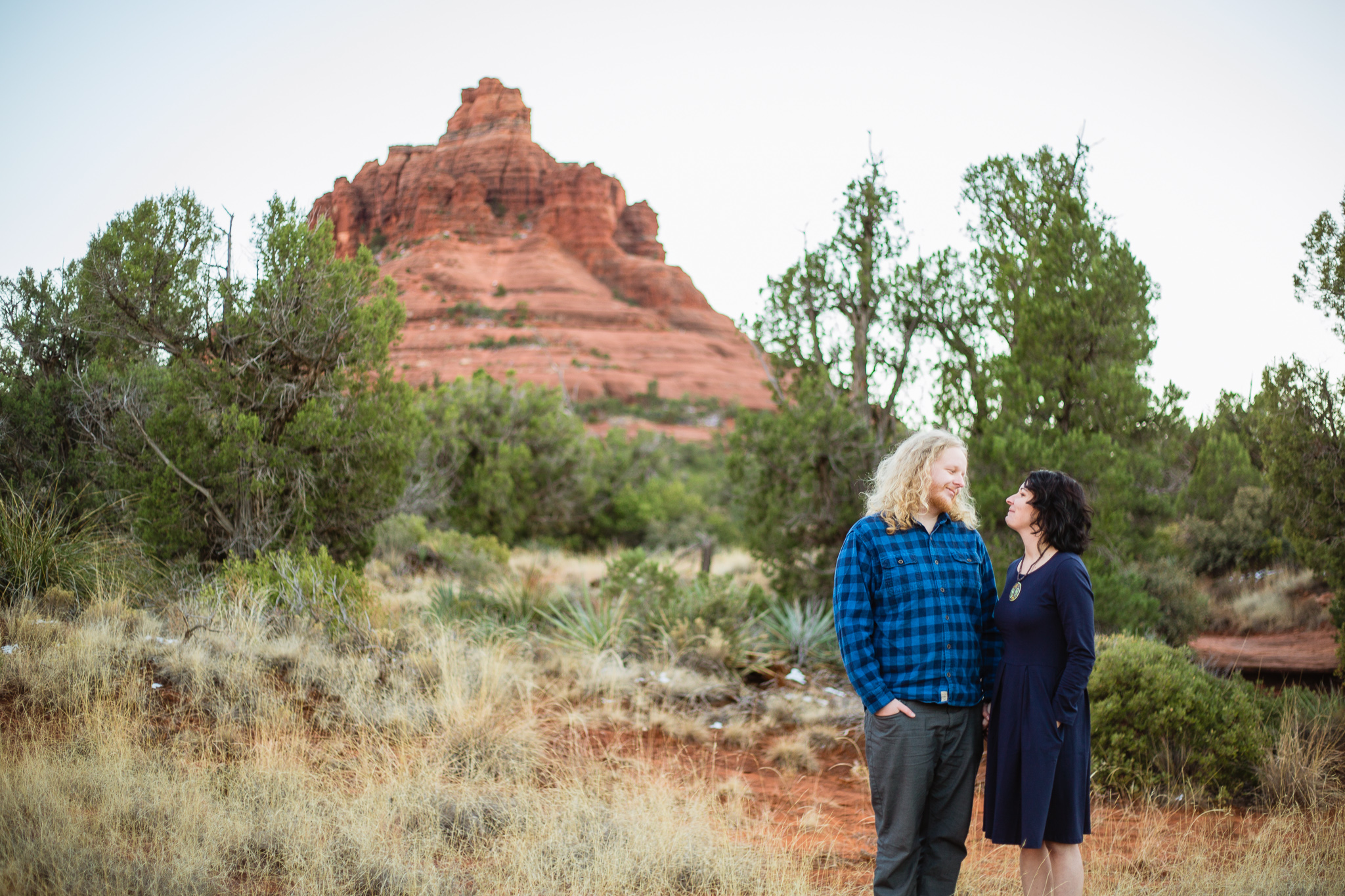 Couple looking at each other in navy blue and grey outfits at their Bell Rock Engagement session by PMA Photography.
