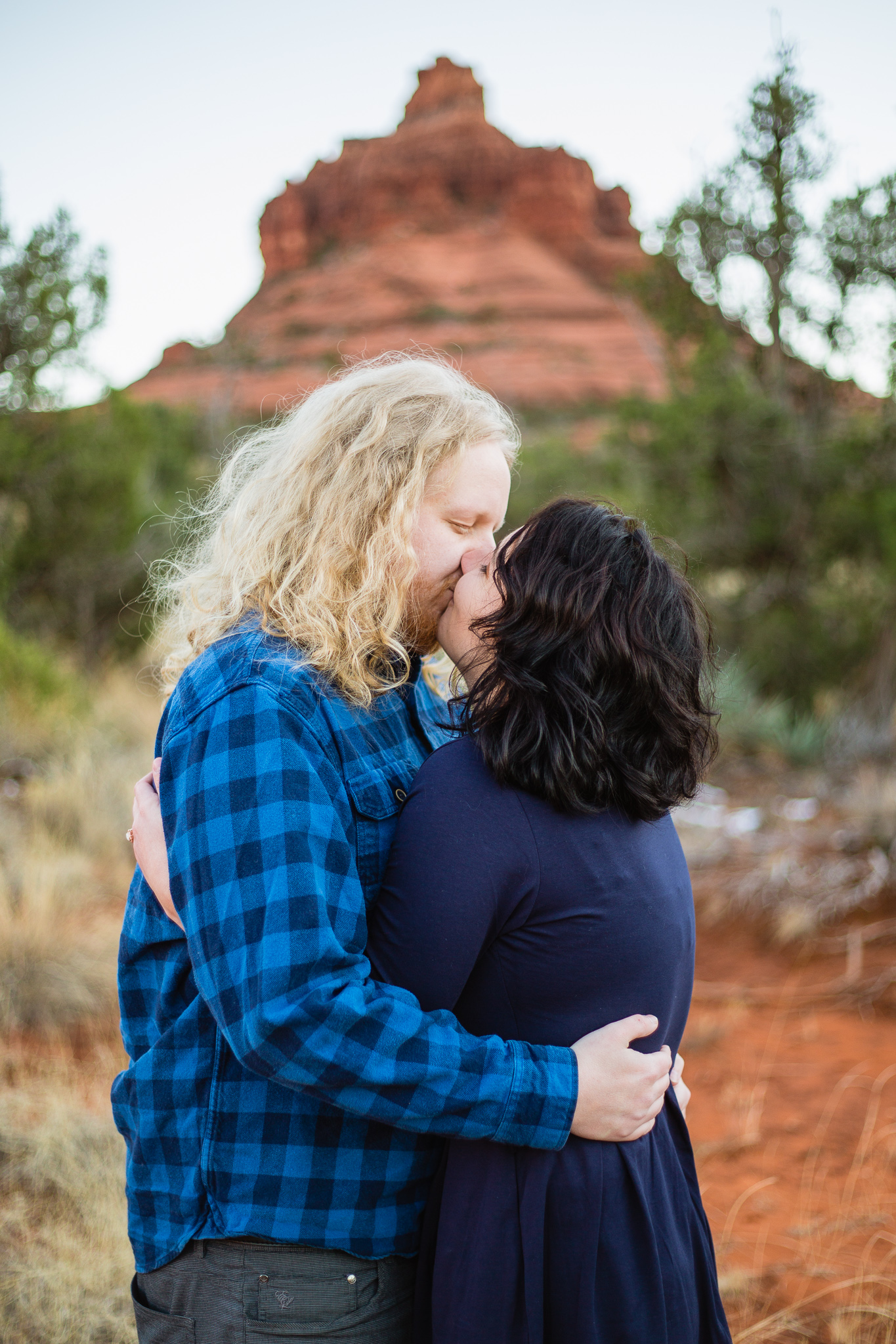 Couple kissing in front of Bell Rock by Sedona engagement photographer PMA Photography..