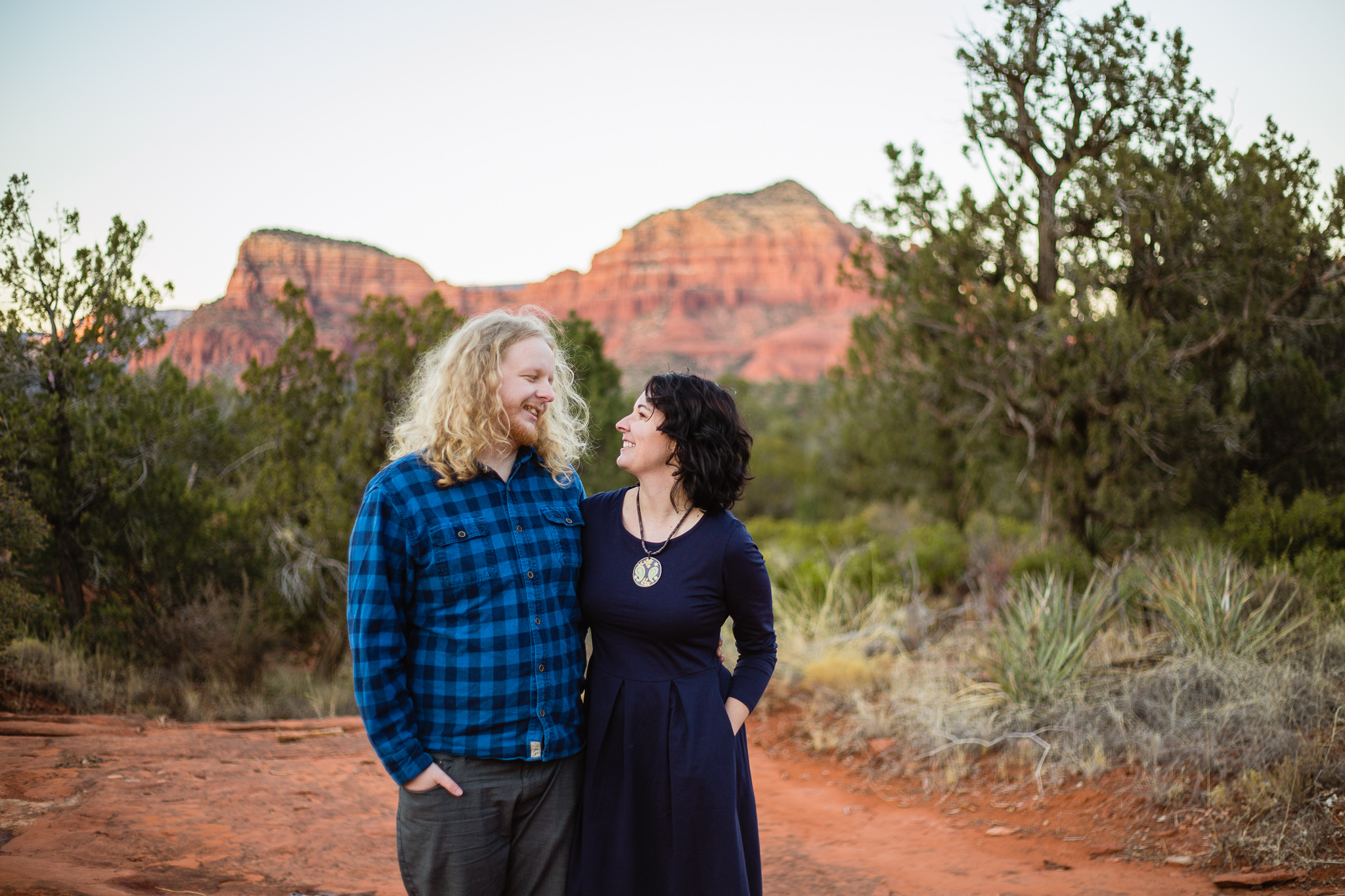 Couple looking at each other in navy blue and grey outfits at their Engagement session in Sedona by PMA Photography.