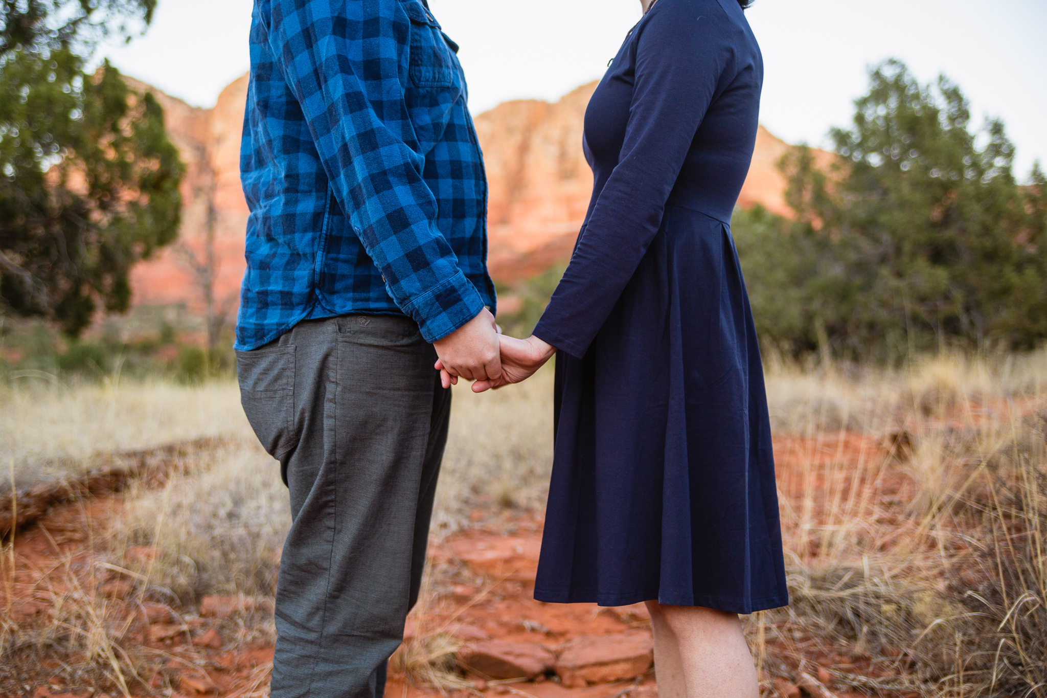 Close up image of couple holding hands during their engagement session in Sedona by PMA Photography.
