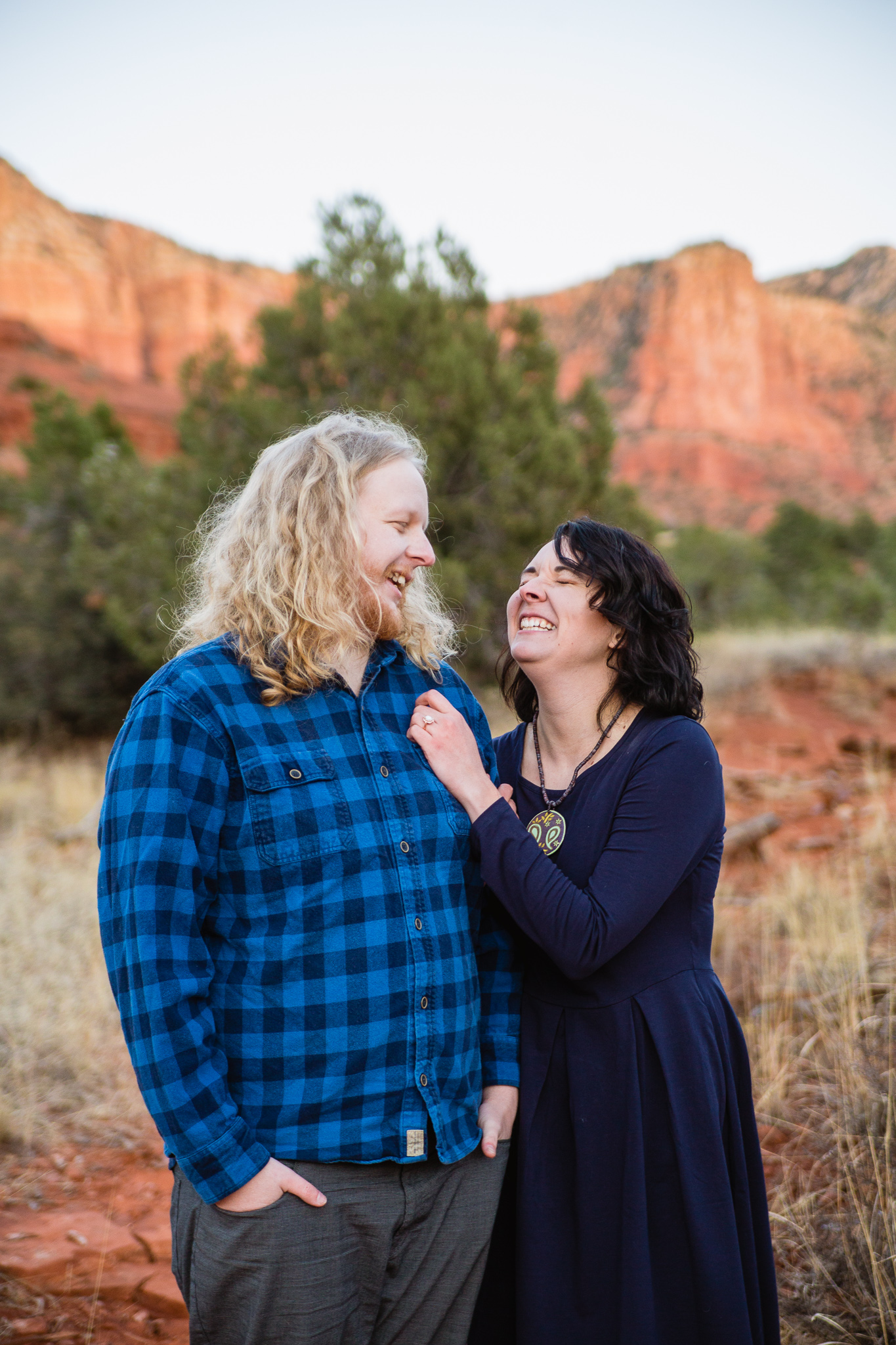 Couple laughing together during engagement session surrounded by the red rocks of Sedona by PMA Photography.