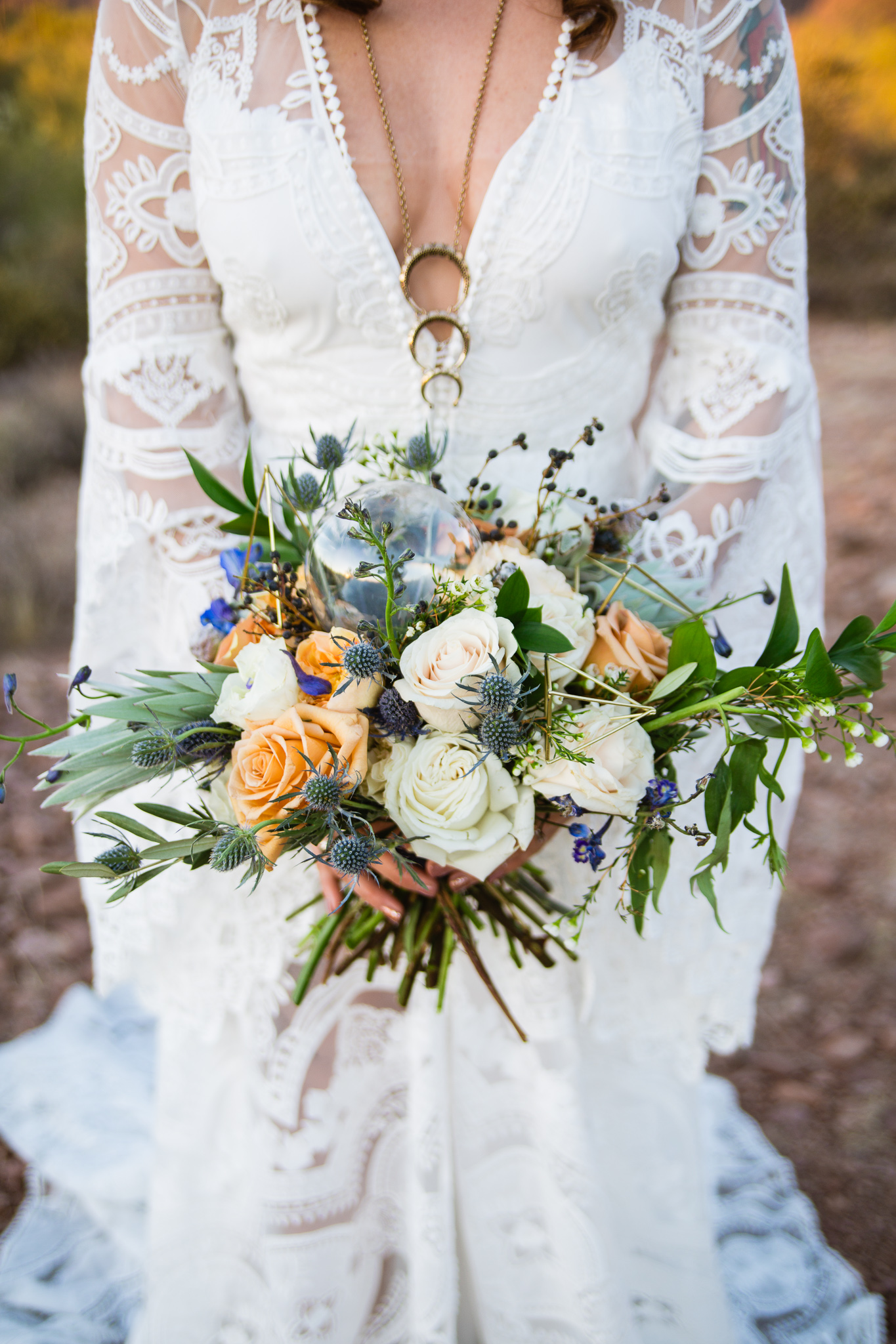 Boho witchy white blue sage and golden bouquet with gold triangles and a crystal ball by Moelleux Events at the Superstition Mountains held by bride in a bohemian rue de seine wedding dress..