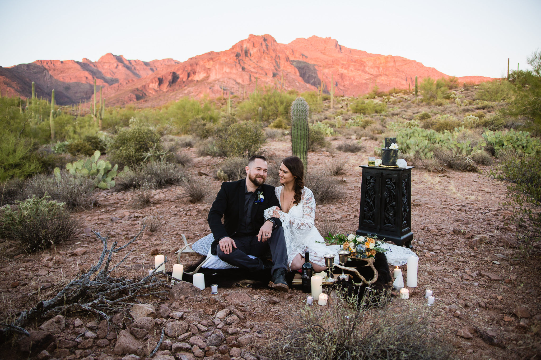 Witchy bohemian inspired bride and groom sharing hors d'oevres and wine at a Superstition Mountains styled wedding surrounded by the beauty of the desert.