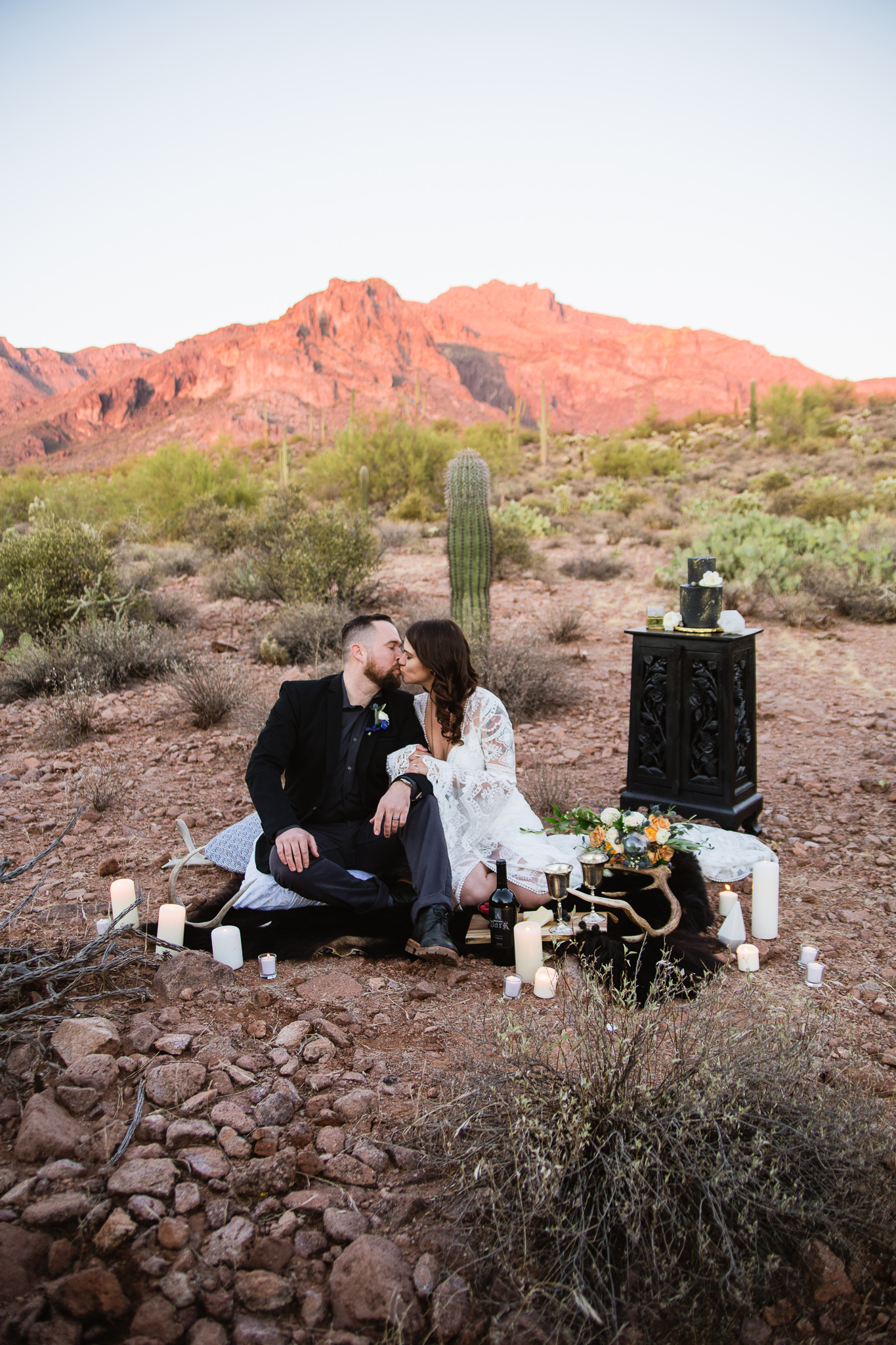 Withcy boho inspired bride and groom sharing wine and hors d'oeuveres at a superstition mountains styled wedding.
