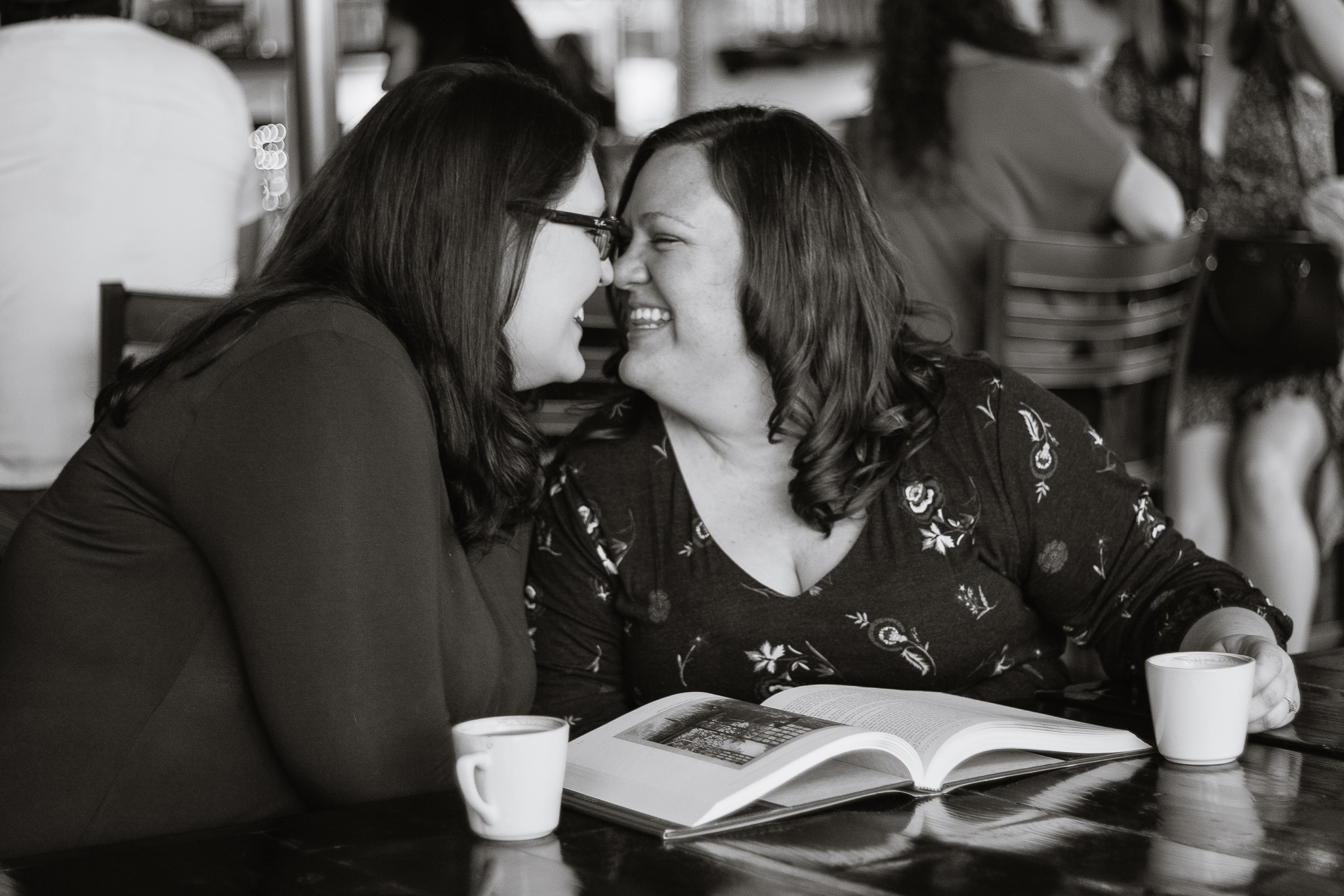 LGBTQ couple reading a book and drinking coffee during their engagement session at Jobot coffee shop in Phoenix.