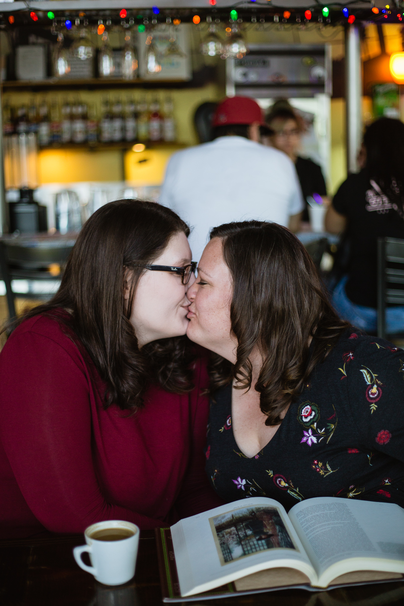 LGBTQ couple reading a book and drinking coffee during their engagement session at Jobot coffee shop in Phoenix.