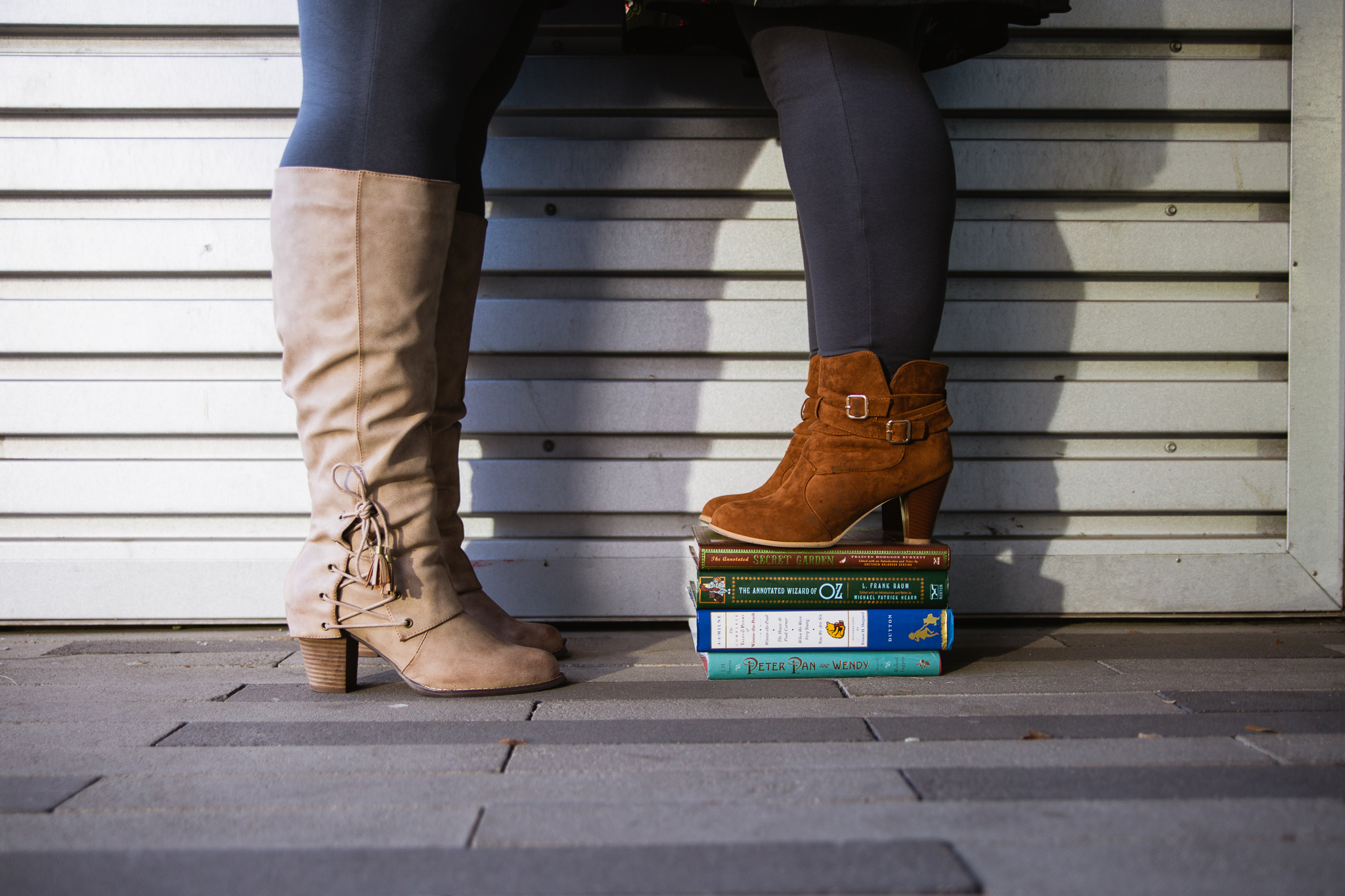 LGBTQ couple in tan boots standing on books during their engagement session.